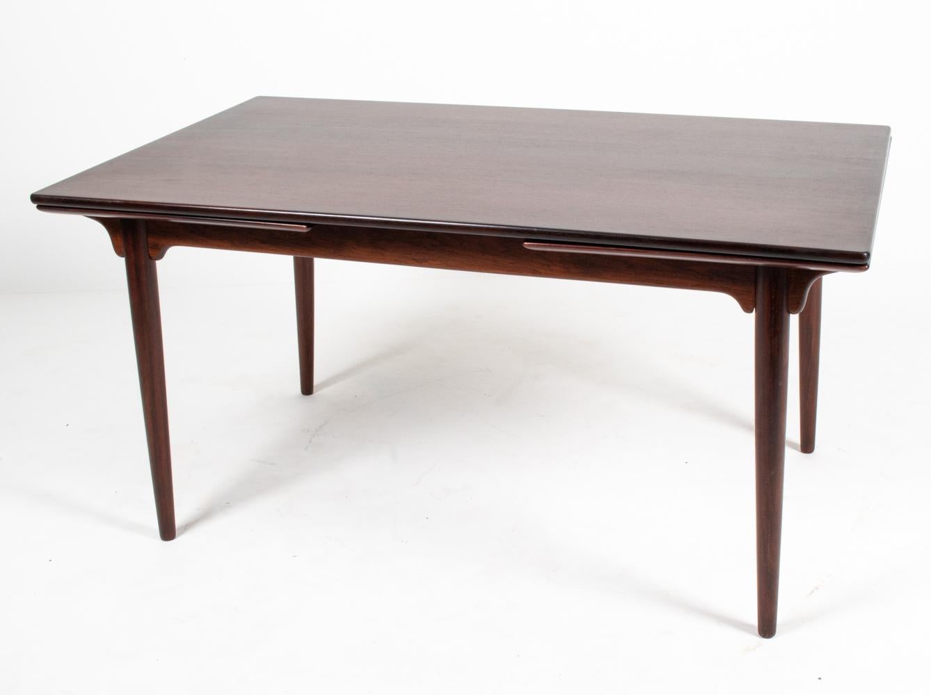 Turn your dining room into a destination with this exquisite dining table by Gunni Omann for Omann Jun, which features a Dutch-style draw leaf top supported by elegant tapered legs and subtle bracket-style braces. The table is finished in dark, rich