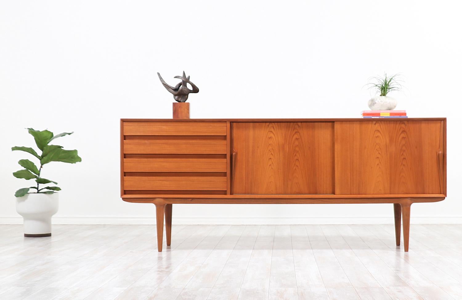 Stunning modern credenza designed by Gunni Omann for family-owned company Omman Jun in Denmark circa 1960s. The low in profile and sculptural Model-18 credenza features a sturdy case with a fully finished back and warm tones that beautifully enhance