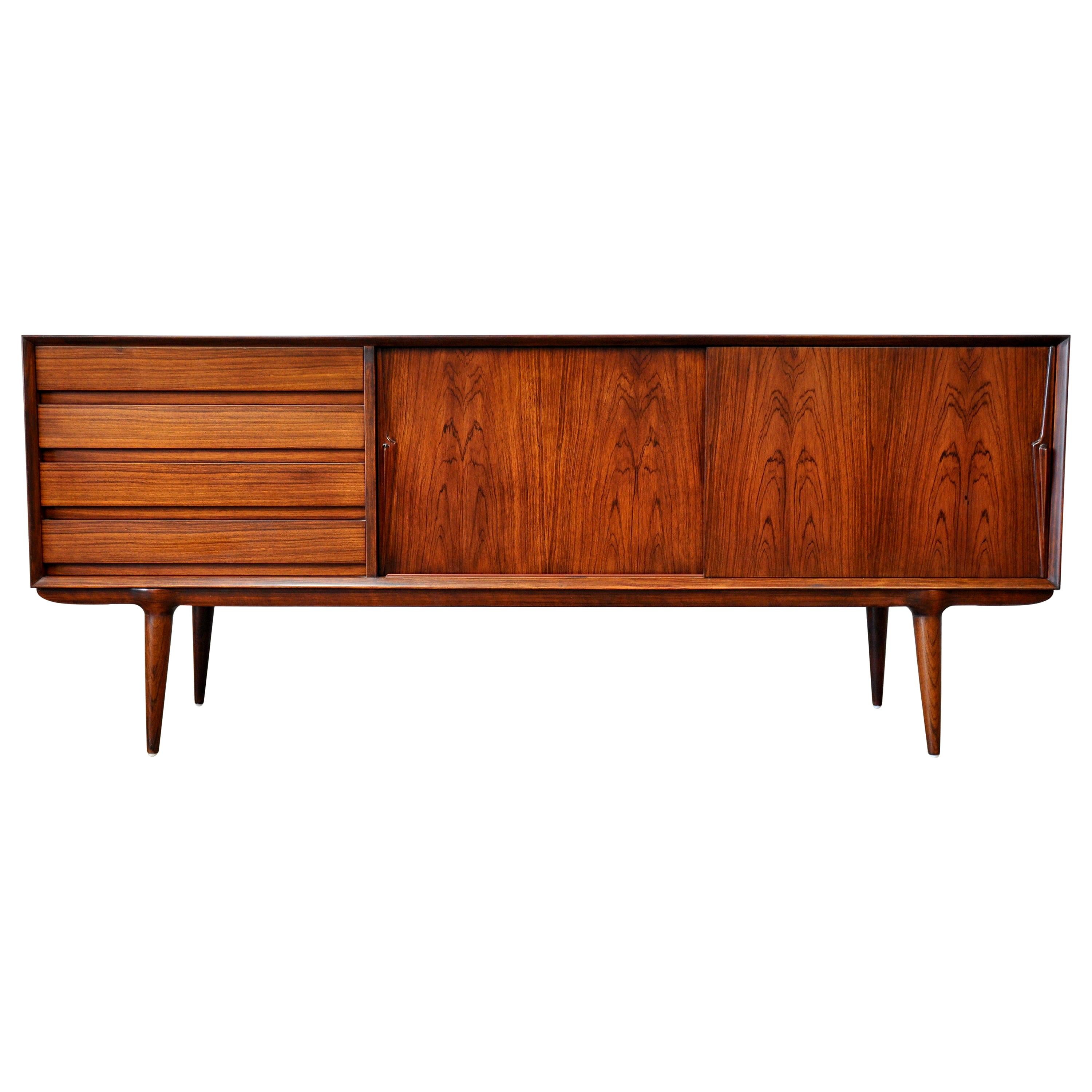 Outstanding midcentury Danish modern rosewood sideboard or buffet designed by Gunni Omann for Omann Jun Møbelfabrik, dating from the 1960s. This stunning credenza features a striking silhouette and low profile design with tapering and elegantly