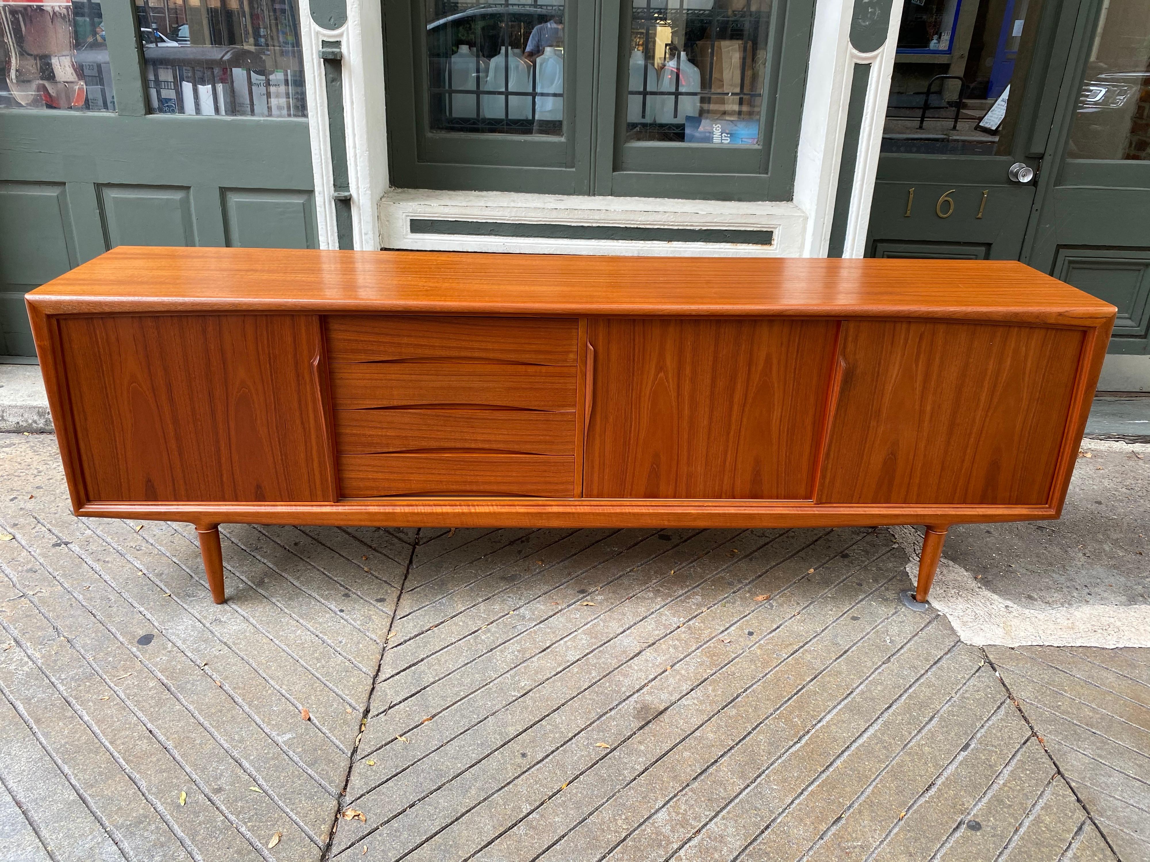 Gunni Omann teak credenza for Axel Christiansen, extra long and sleek! Beautiful credenza with sliding doors and pull out felt lined drawers in the center. Outstanding grain throughout! Quite the looker! Measures: 95