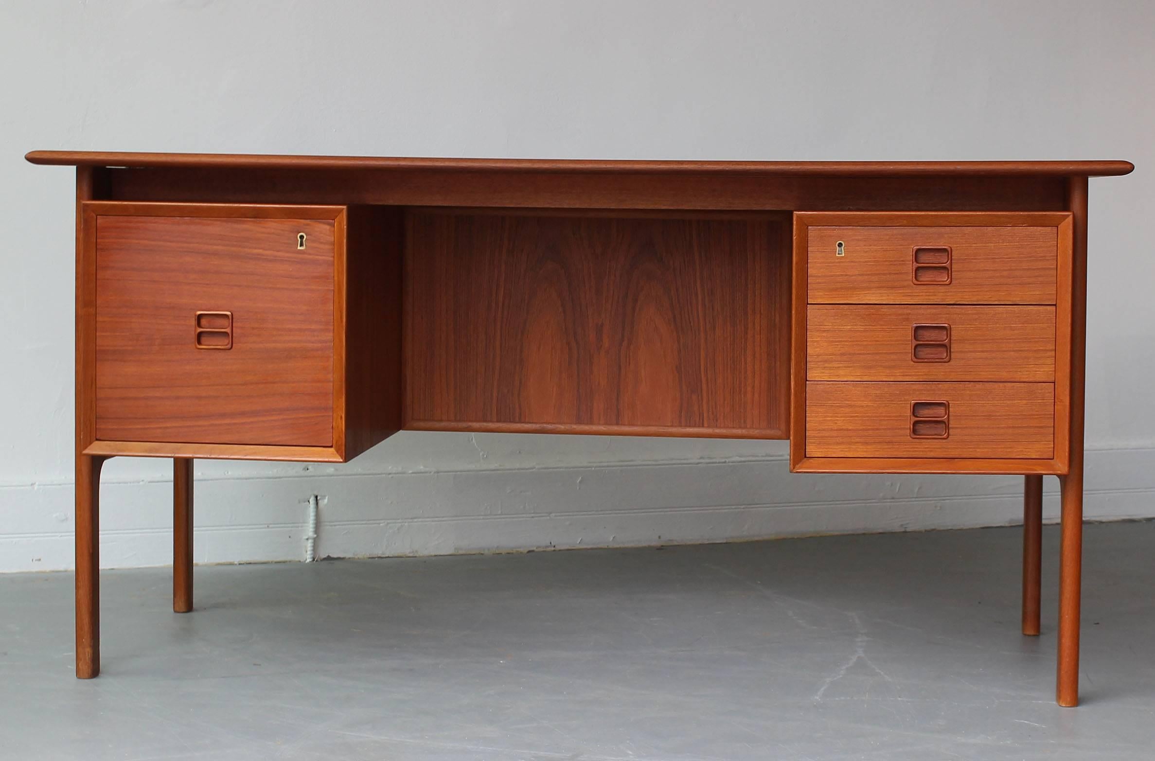 Teak desk designed by Gunni Omann, for Omann Jun Mobelfabrik, circa 1960s, Denmark. Rear open shelving with floating drawers and central teak divider. Lightly and lovingly restored.