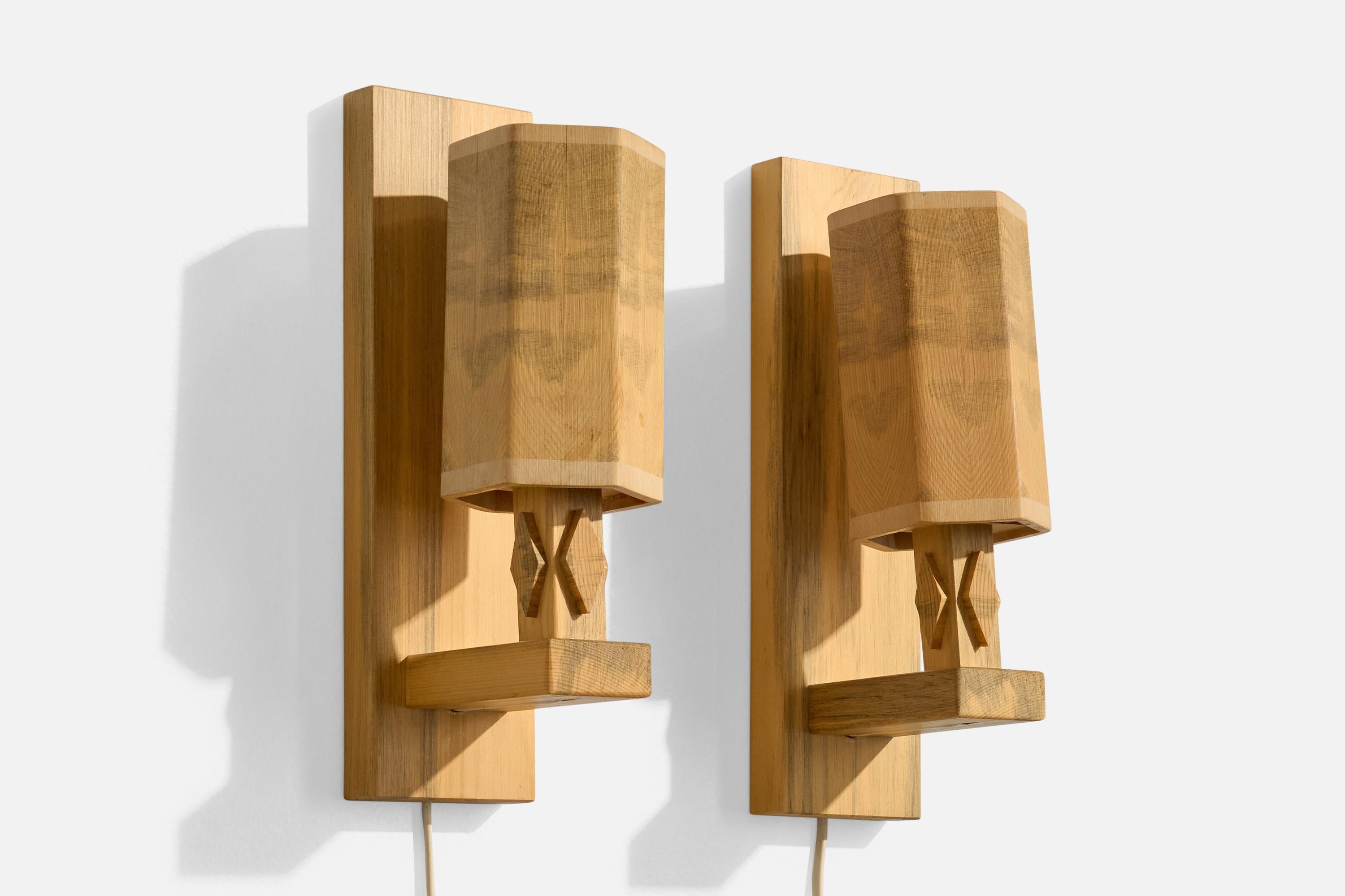 A pair of wood wall lights designed and produced by Guns Hemslöjd, Sweden, c. 1970s.

Overall Dimensions (Inches): 11” H x 3.125” W x 4.75” D

Back Plate Dimensions (Inches): 11” H x 3.125“ W x .9” D

Bulb Specifications: E-14

Number of Sockets