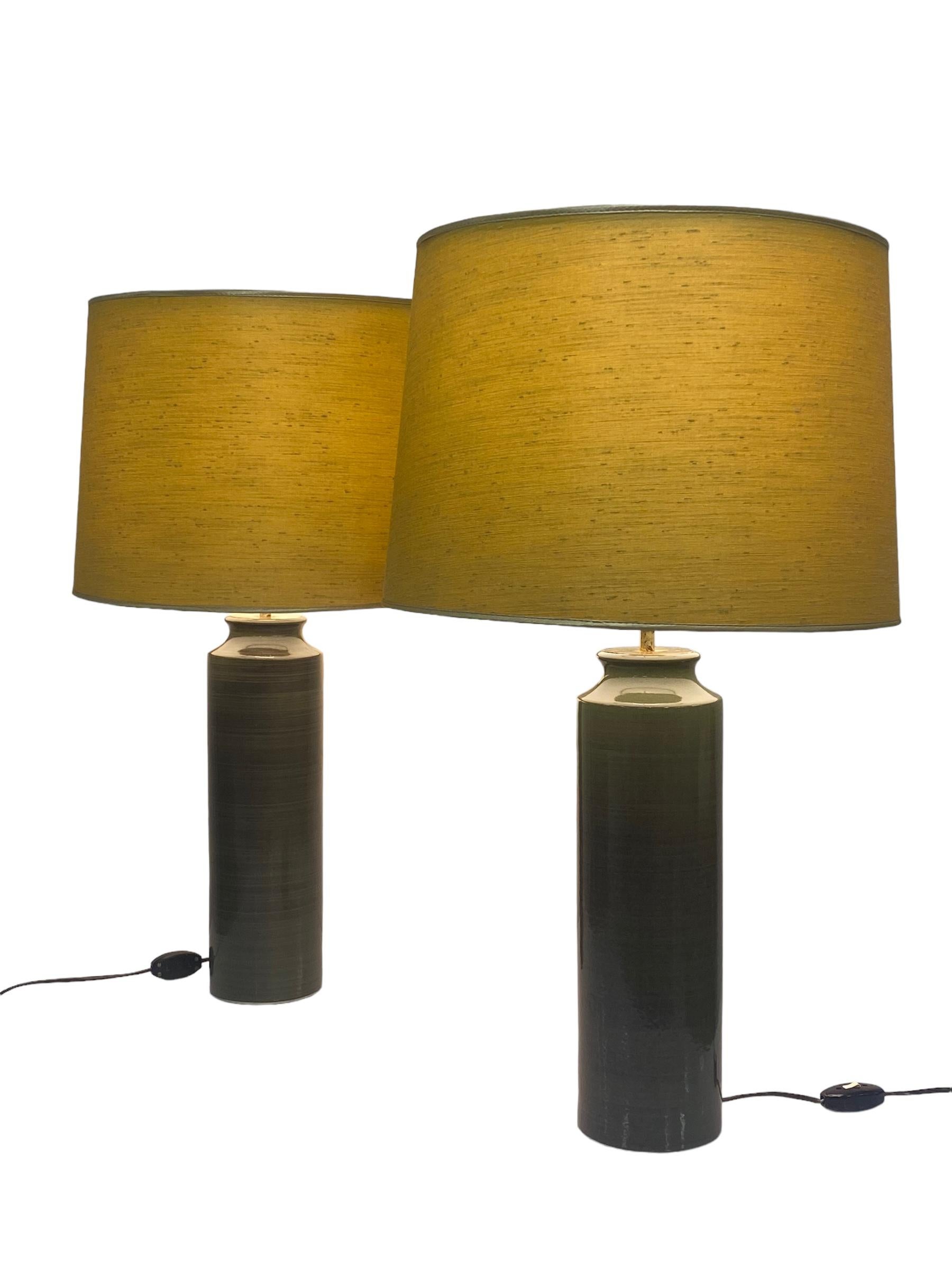 Zwei majestätische Tischlampen, entworfen von Gunvor Olin-Grönqvist für Arabia in den 1950er Jahren. Die Lampen sind sehr groß und ausgeprägt. Mit einem grünlichen Keramikfuß und gelben Stoffschirmen. Beide Lampen tragen die Aufschrift 