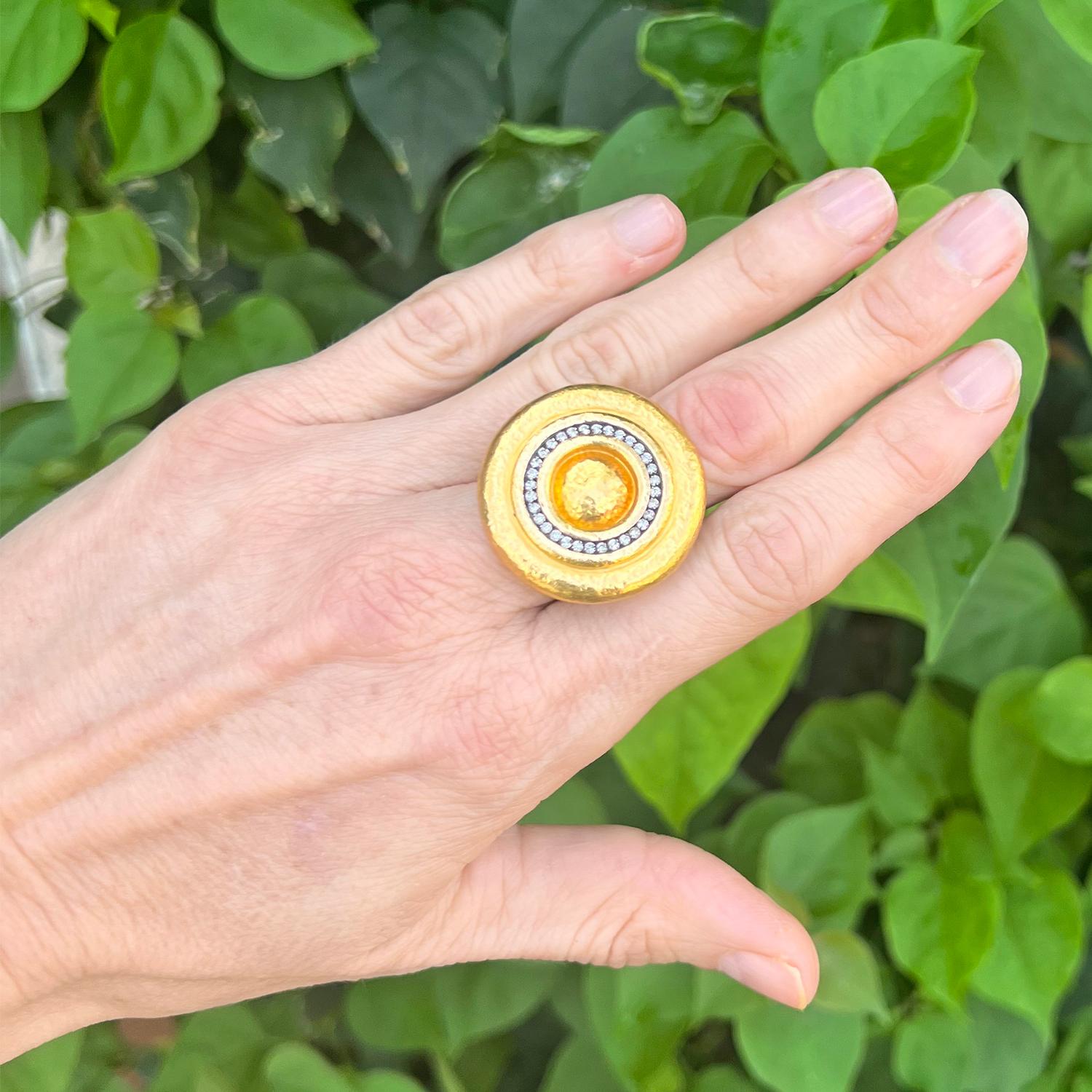 A 22k yellow gold cocktail ring, designed as a bold hammered gold disc in a concentric circle motif, one circle set with thirty-two round brilliant-cut diamonds, the disc atop a wide hammered gold band.

Diamonds weighing approximately 0.72 total