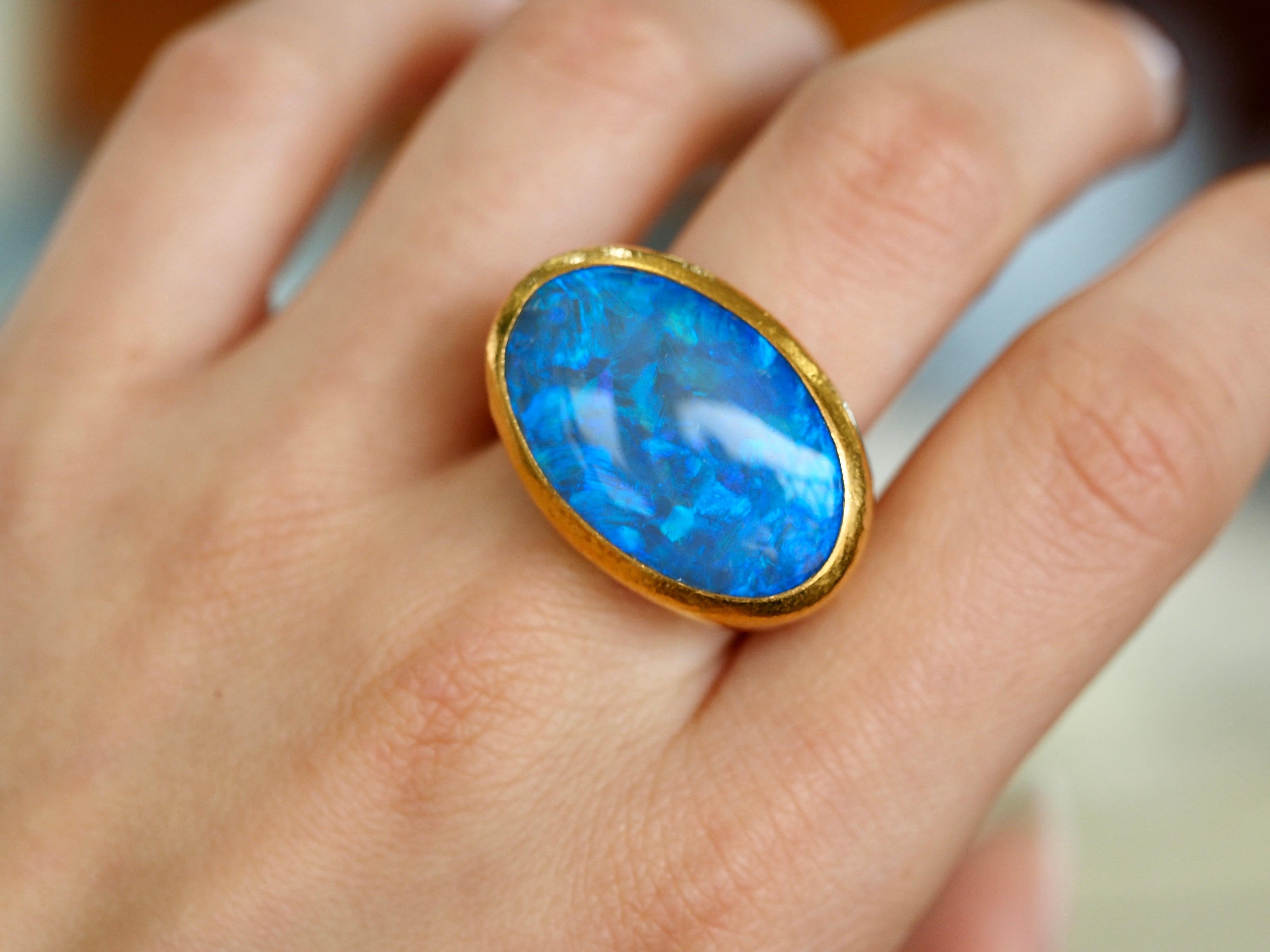Gurhan one-of-a-kind 24-karat Australian opal ring is absolutely breath taking. The signature 24-karat yellow gold has a hammered finish that catches the light at all angles. The bezel set oval opal center is a blend of blues, purples and greens in