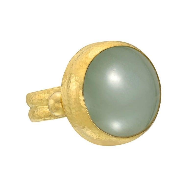 Cabochon green-hued aquamarine cocktail ring, the aquamarine measuring approximately 18mm in diameter, in hammered 24k yellow gold, signed Gurhan. Size 7.