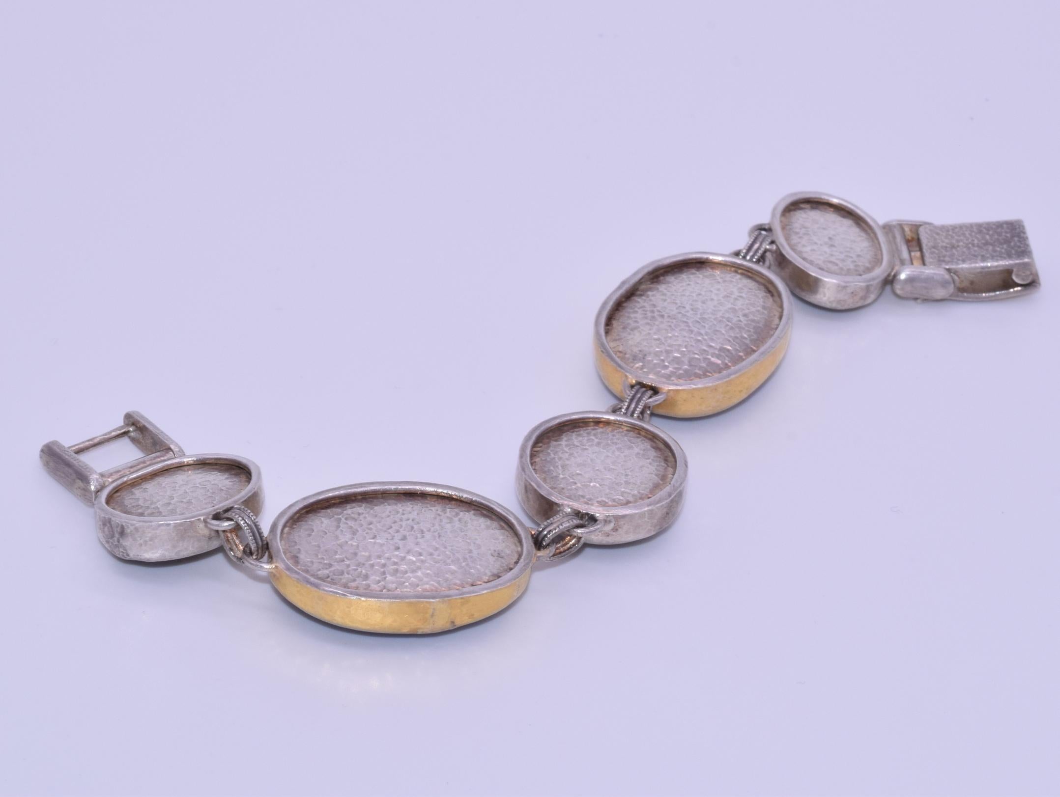 Five cabochon labradorite stones alternating in size are set in sterling silver and 24K yellow gold hand-hammered bezels featuring a two tone clasp signed Gurhan. Length: 7in, 22.85mm at the widest point.