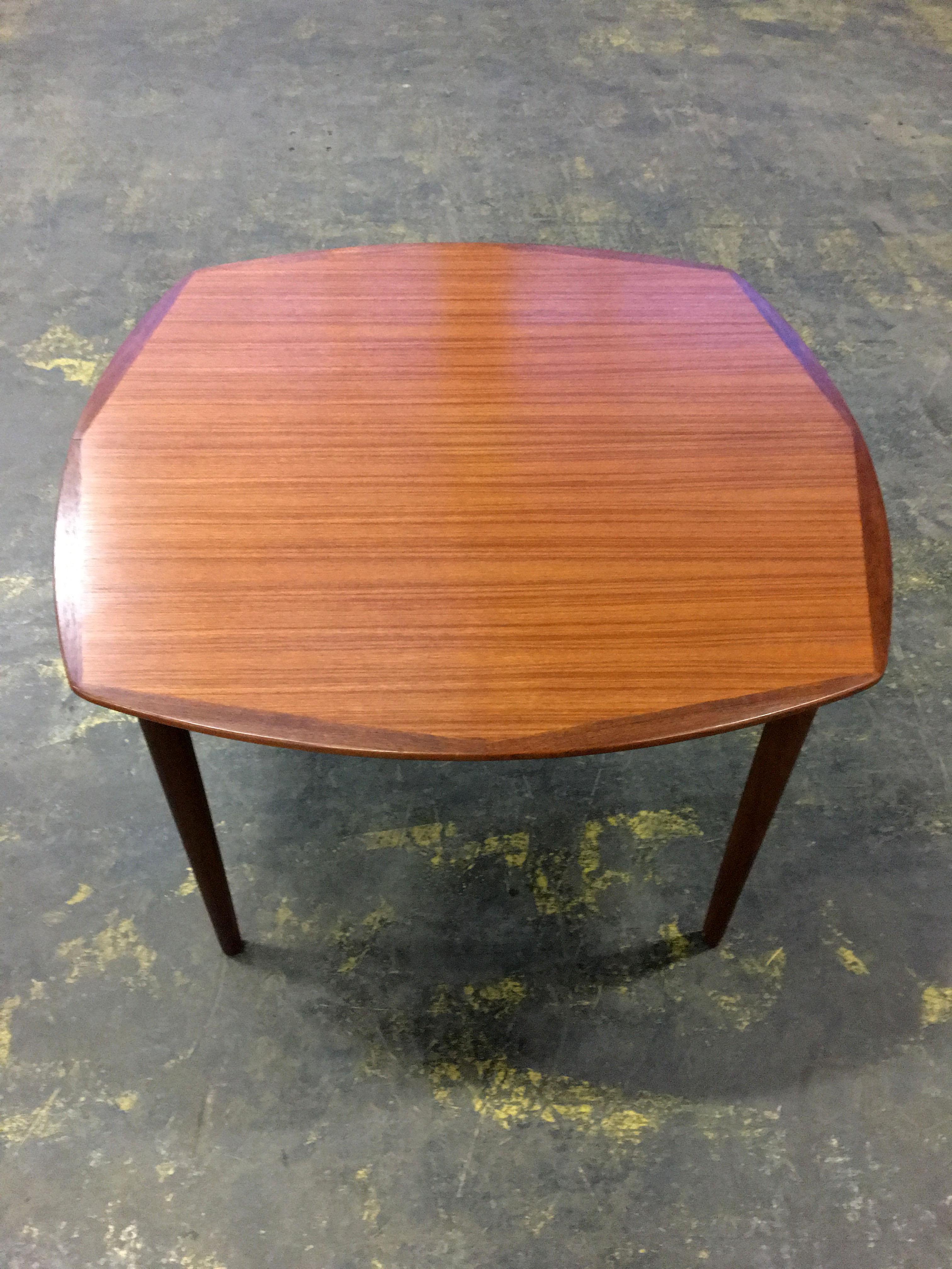 A lovely Scandinavian dining table by Gustav Bahus, Norway 1960s. Not square nor circular, the table mixes both shapes to create a beautiful unusual design. The table top is framed by a corner edge, accented in a darker shade of teak. The legs
