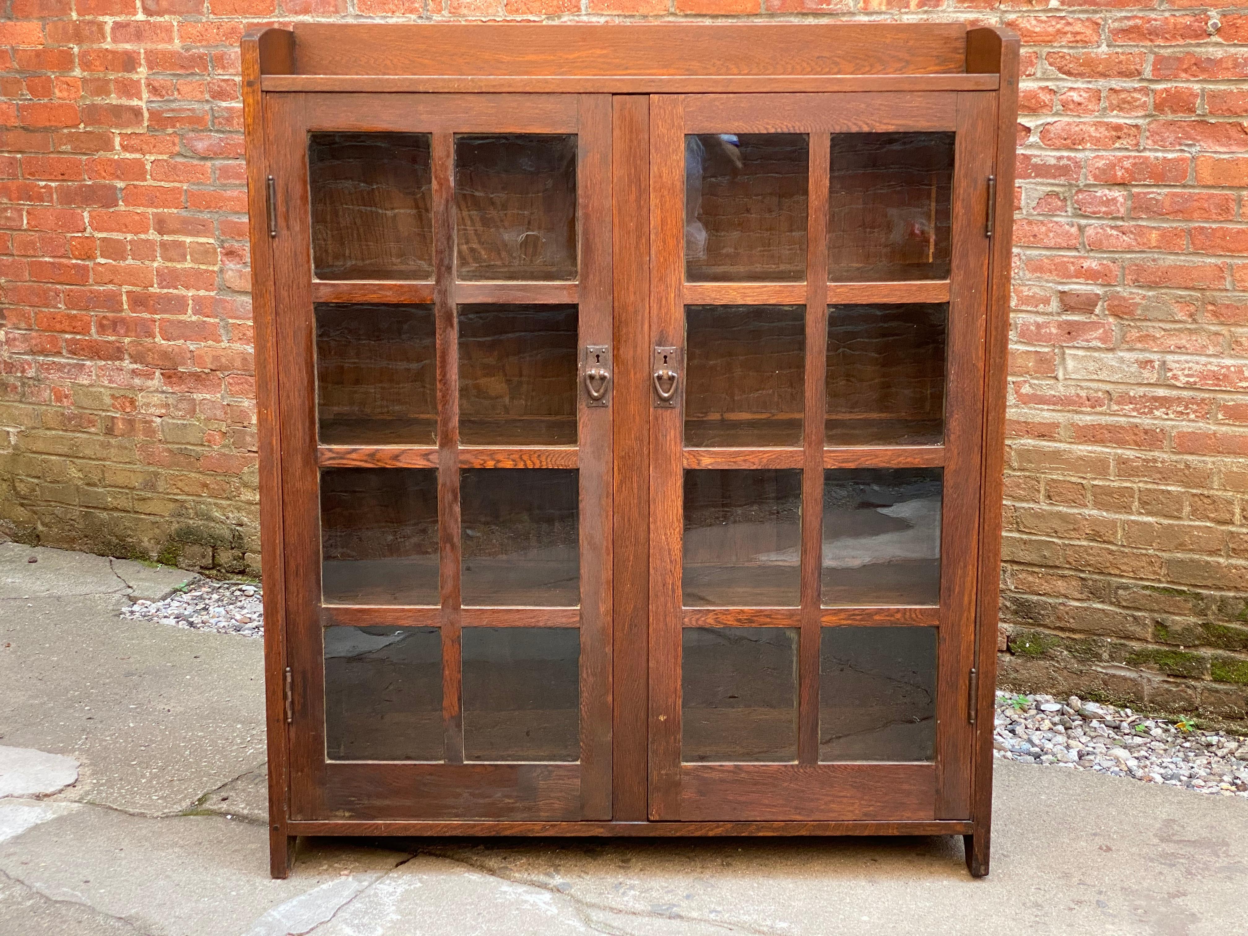 Gustav Stickley #717 American quarter sawn oak double door bookcase. Original handwrought copper hardware, glass and finish. Exposed Tenon and dowel construction. The mullions are all in line with the fixed book shelves, which is a wonderful Gustav