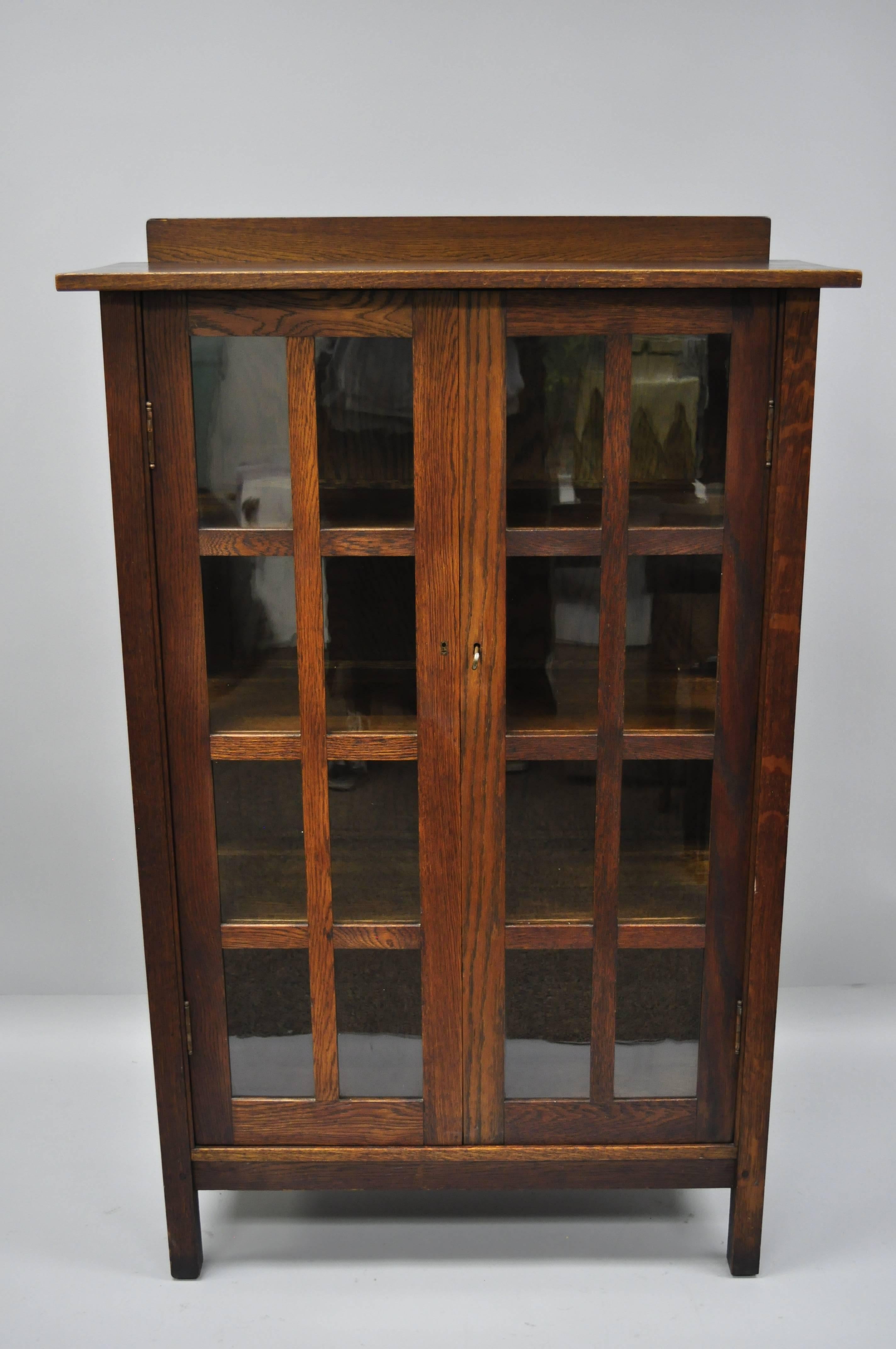 Authentic Gustav Stickley Mission Arts & Crafts oak and glass two-door China cabinet. Item features solid oak wood construction, beautiful wood grain, two swing doors with eight panes of glass each, glass sides with four panes of glass each, total