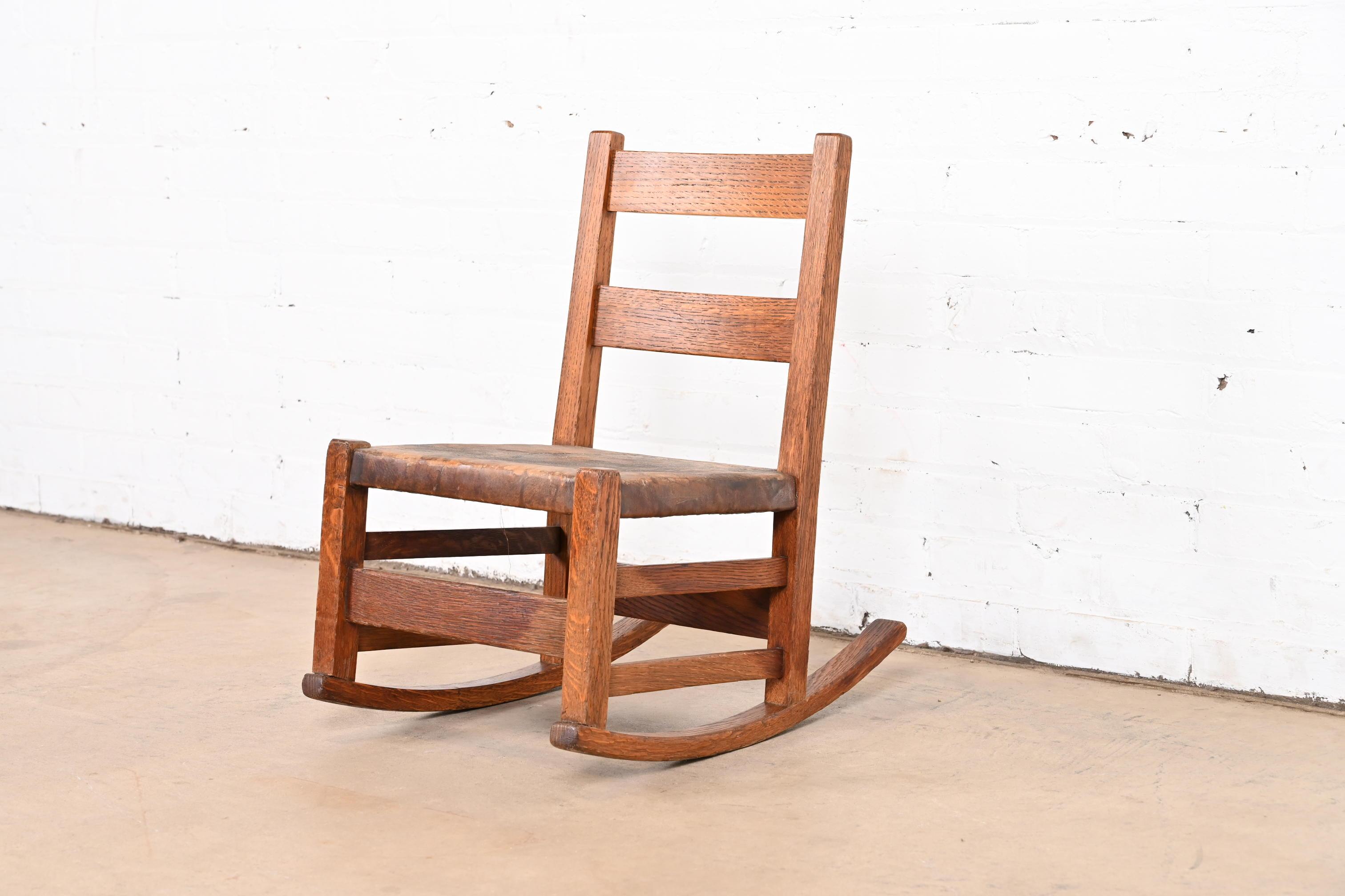 A gorgeous Mission oak Arts & Crafts child's rocking chair

By Gustav Stickley (partial label present on underside)

USA, Circa 1900

Solid quarter sawn oak, with original brown leather seat.

Measures: 14