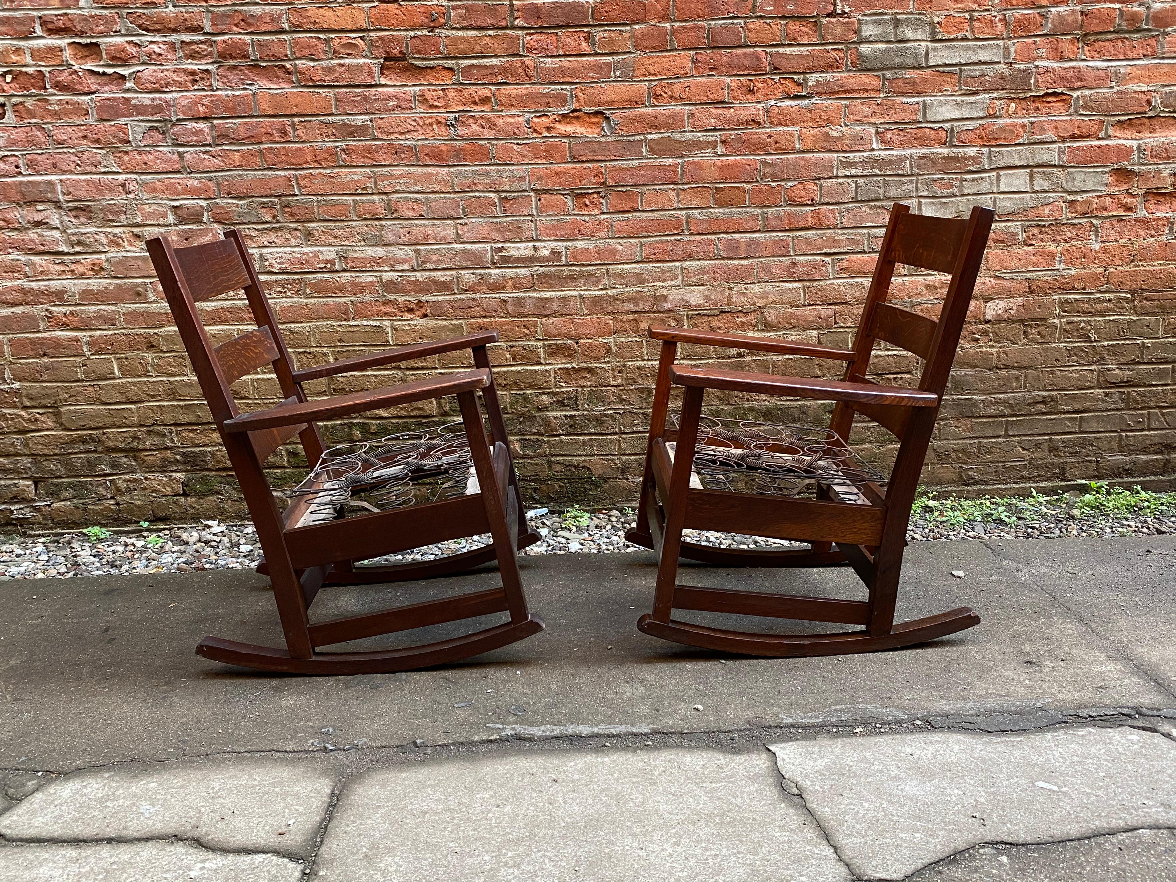 A fine pair of solid oak Gustav Stickley rocking chairs. Excellent dark original finish. Structurally sound and sturdy frames. Mortise and tenon and dowel construction. Original drop in spring seat I am having the seats done in a lightweight cotton