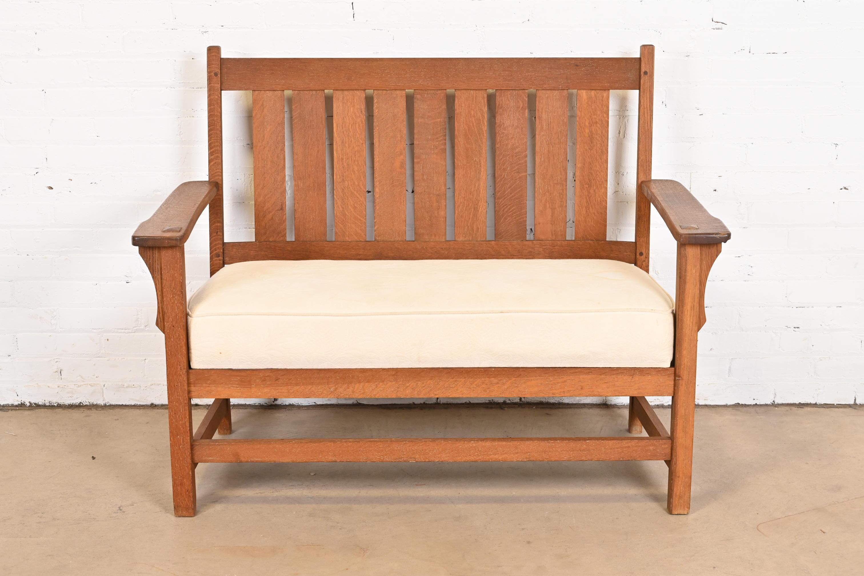 A beautiful Mission or Arts & Crafts loveseat, settee, or bench.

In the manner of Gustav Stickley.

USA, circa 1900.

Solid quarter sawn oak, with cream upholstered seat cushion.

Measures: 48.25