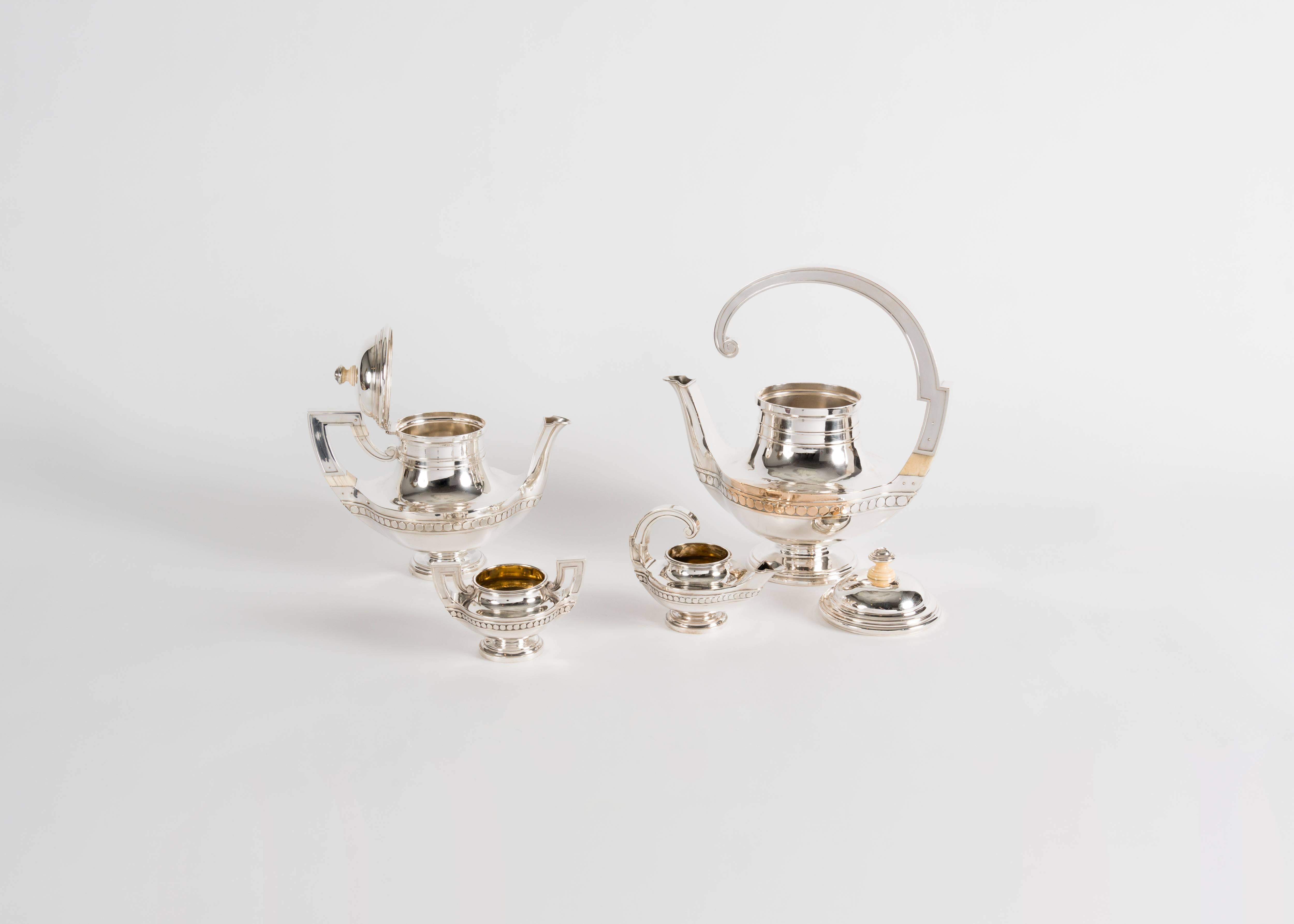 A silver tea set including two tea pots, a creamer, and a sugar bowl, with elegantly arched handles by renowned French silversmith Gustave Keller.