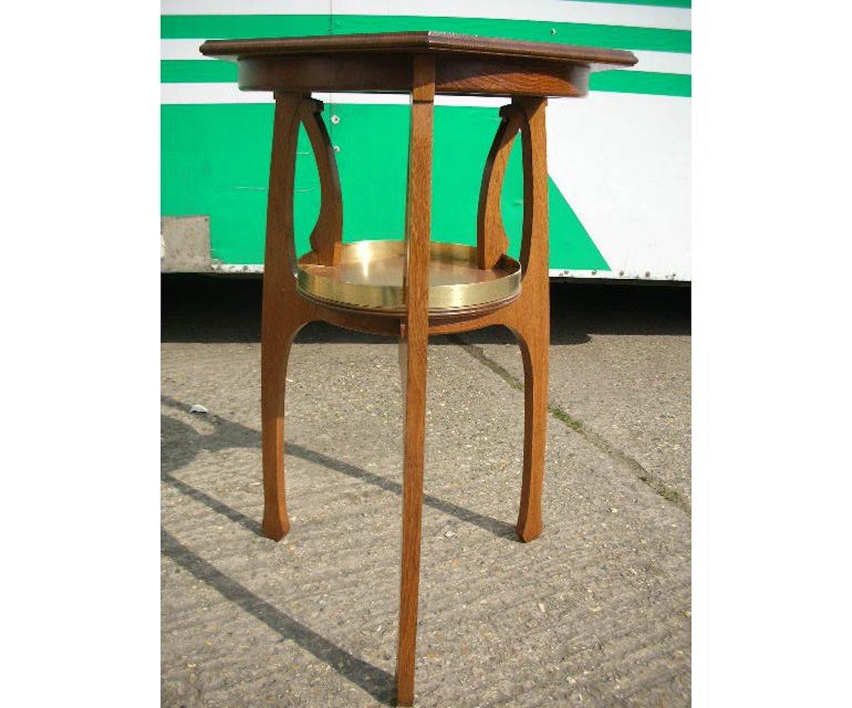 Gustave Serrurier-Bovy Style Off. 
An oak Secessionist side table with six-sided top and brass bound circular lower shelf with organic through supports.
Measures: Height 31 1/2