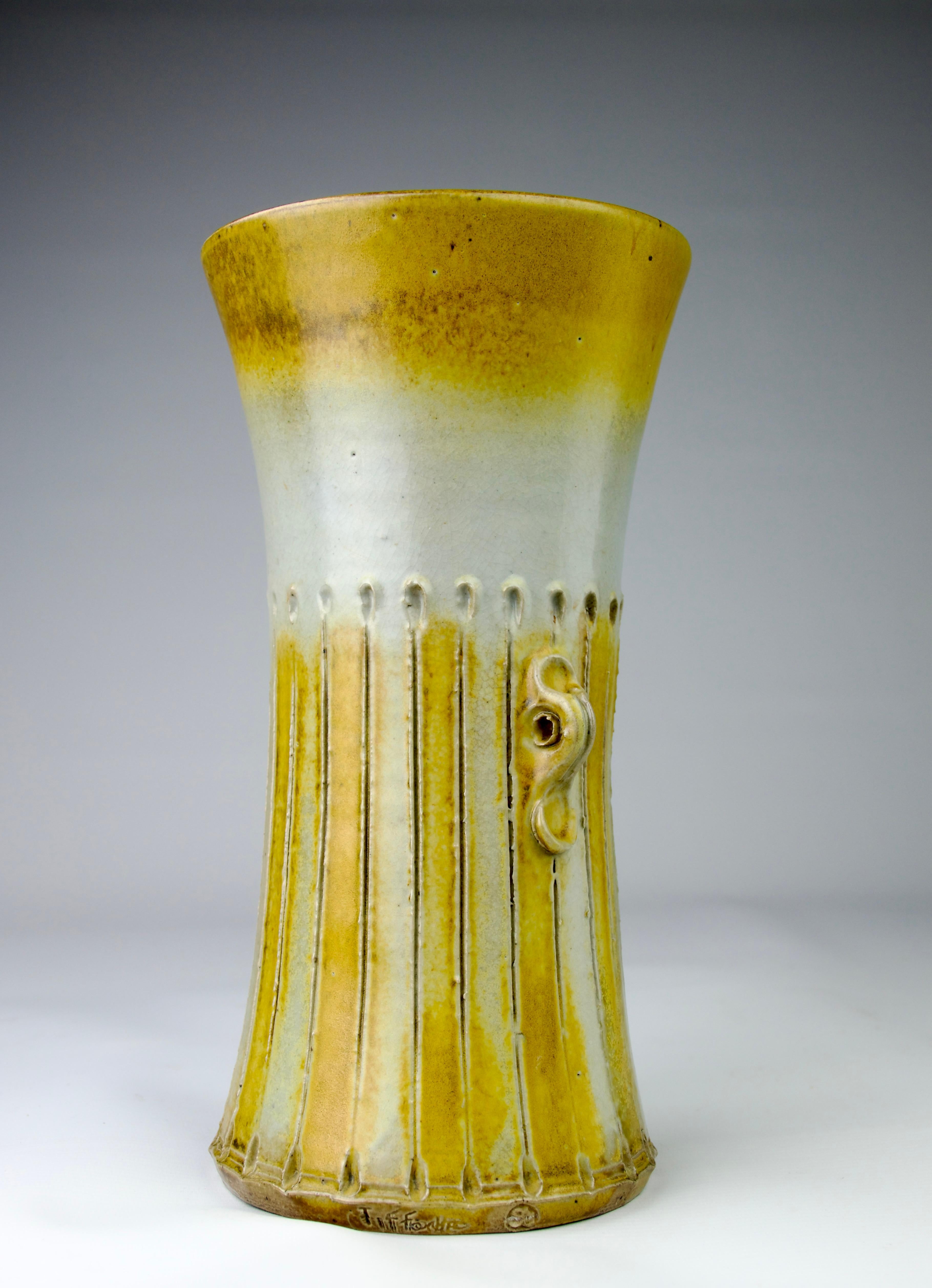 Superbe vase long en grès céramique Gustave Tiffoche. Les décorations striées et les petites poignées sur le côté sont ponctuées de teintes colorées de jaune, de brun et de blanc.

Dimensions en cm (H x P) :  29.2 x 14

En parfait état.

Expédition