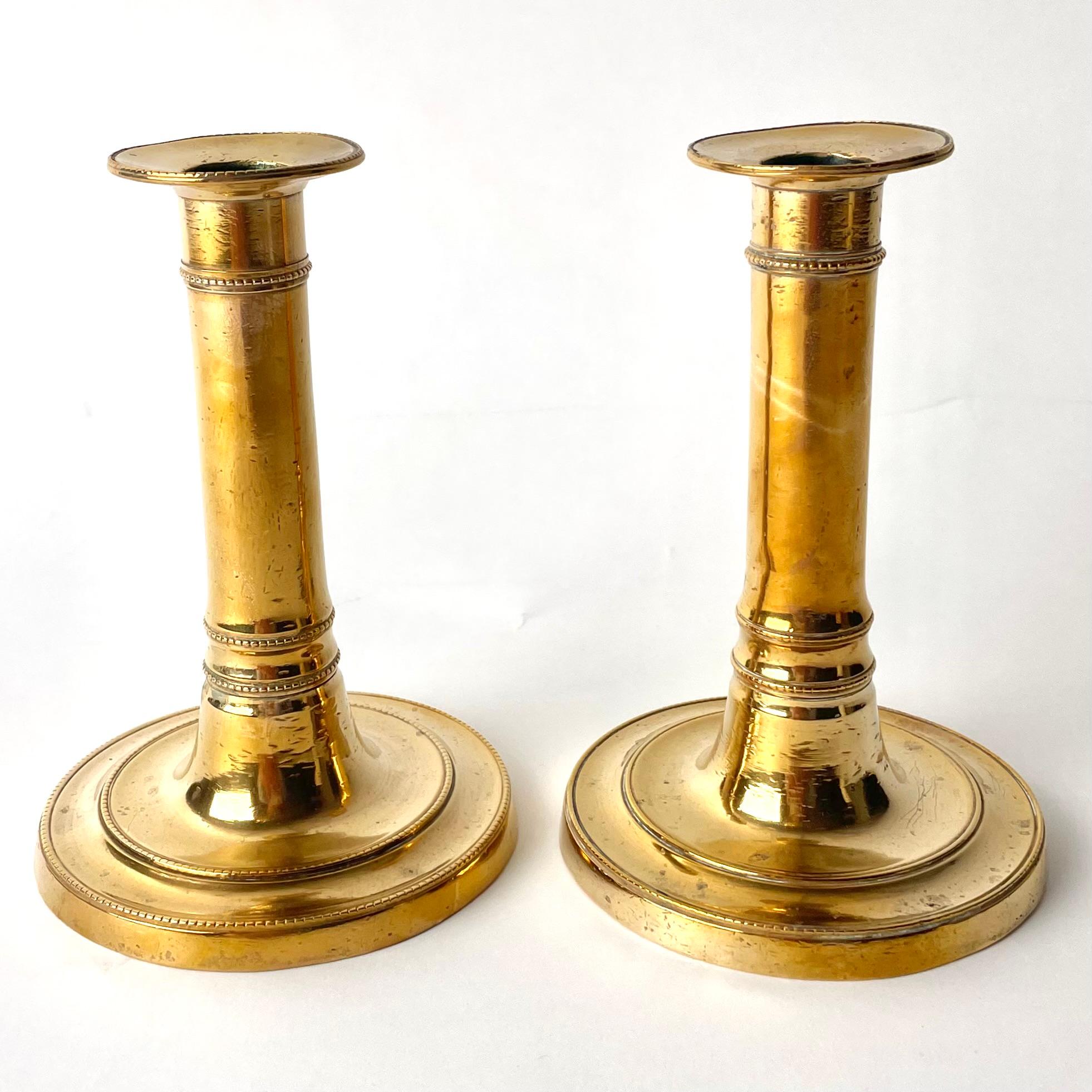 Gustavian Brass Candlesticks. Made in Sweden during the reign of Gustav III. 

The brass used in these candlesticks have high levels of copper, giving the candlesticks a warm golden glow. The ornamentation is typical of Gustavian pieces, reflecting
