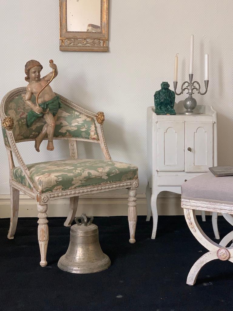 A Swedish Gustavian Bucket Chair. Made in Stockholm about 1790.
Decorated with beautiful lion heads at the armrest and leaf shaped border.
The legs are elegantly carved.
Gently hand scraped and then painted.

Gustavian style was the leading style in