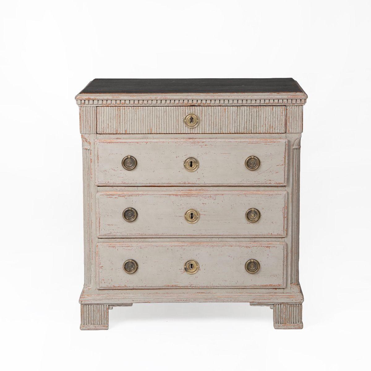 Cómoda de diseño elegante y arquitectónico de estilo Gustaviano, pintada en un suave tono gris con la parte superior pintada de negro y una hermosa pátina.
La parte superior descansa sobre un friso finamente tallado con un motivo dentil clásico.
El