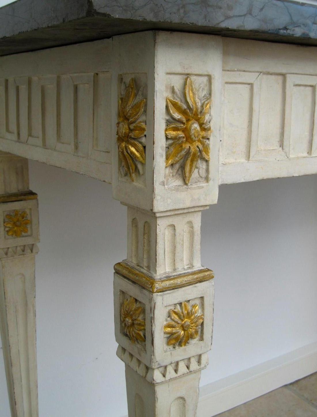 Carved wood with original white paint, carved giltwood rosettes, original grey white-veined marble top. The rectangular top above a Greek key frieze with applied rosettes on square tapering fluted legs and spade feet. The beautiful original grey