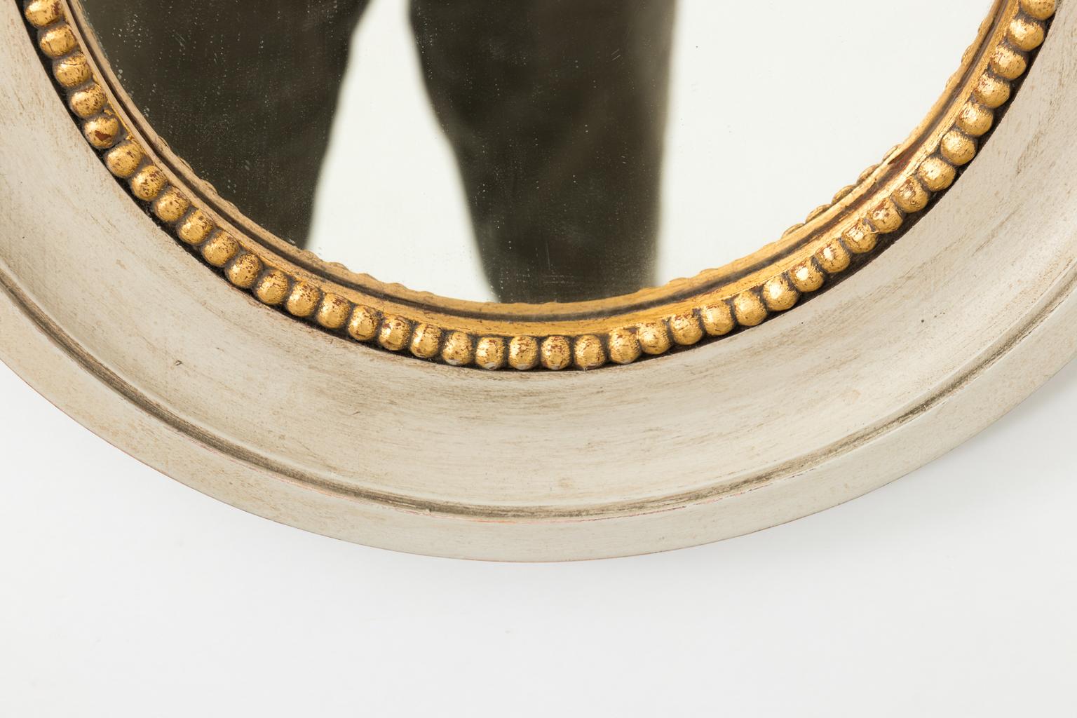 Petite Gustavian grey painted oval mirror with gilded bead trim and carved bow on the crown, circa 1980.
 