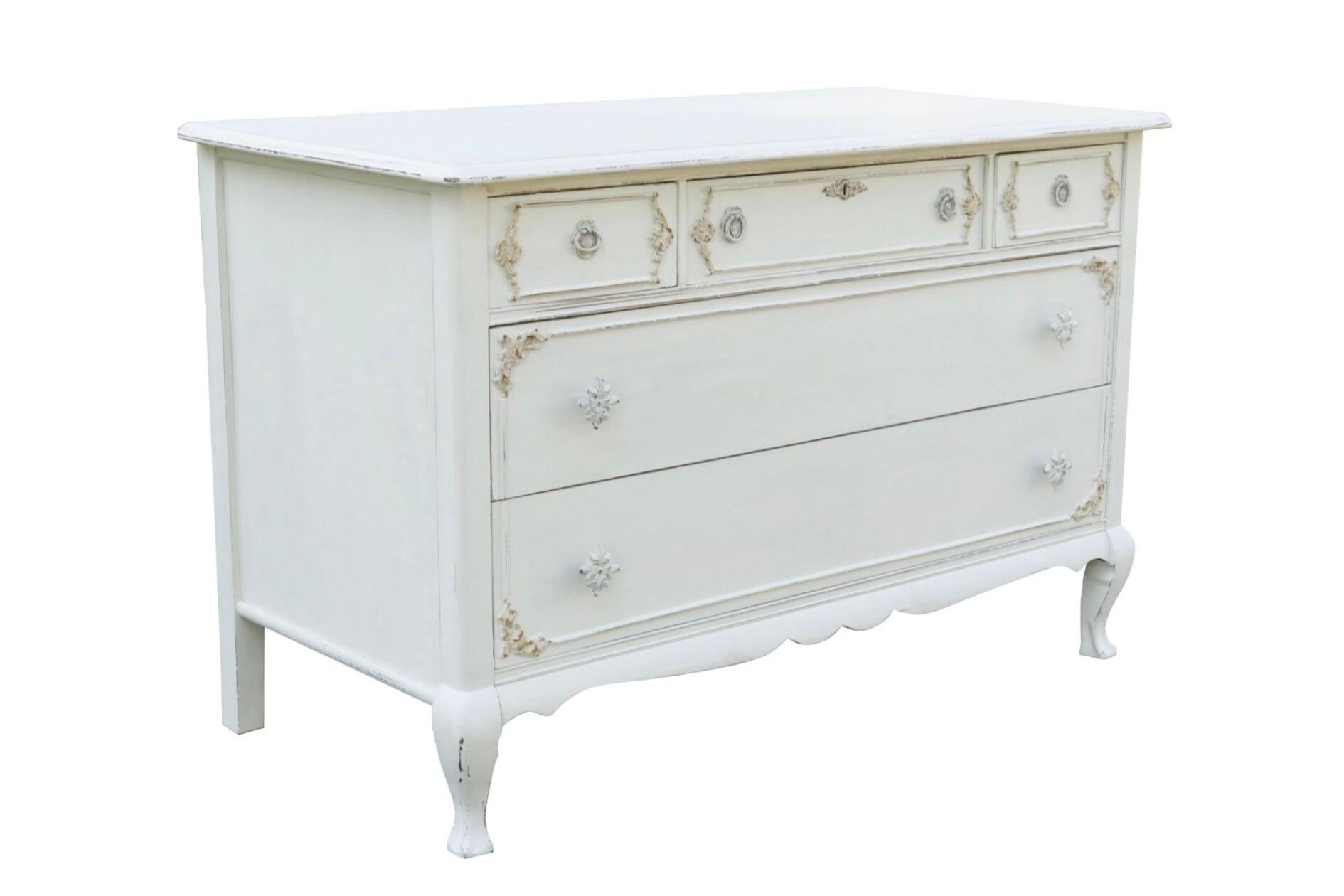 A Gustavian painted Queen Anne dresser. Three over two drawers are dovetailed, opening with pressed pull handles above and floral knob handles below. Drawer fronts are decorated with beveled and carved paneling. A simple serpentine skirt meets