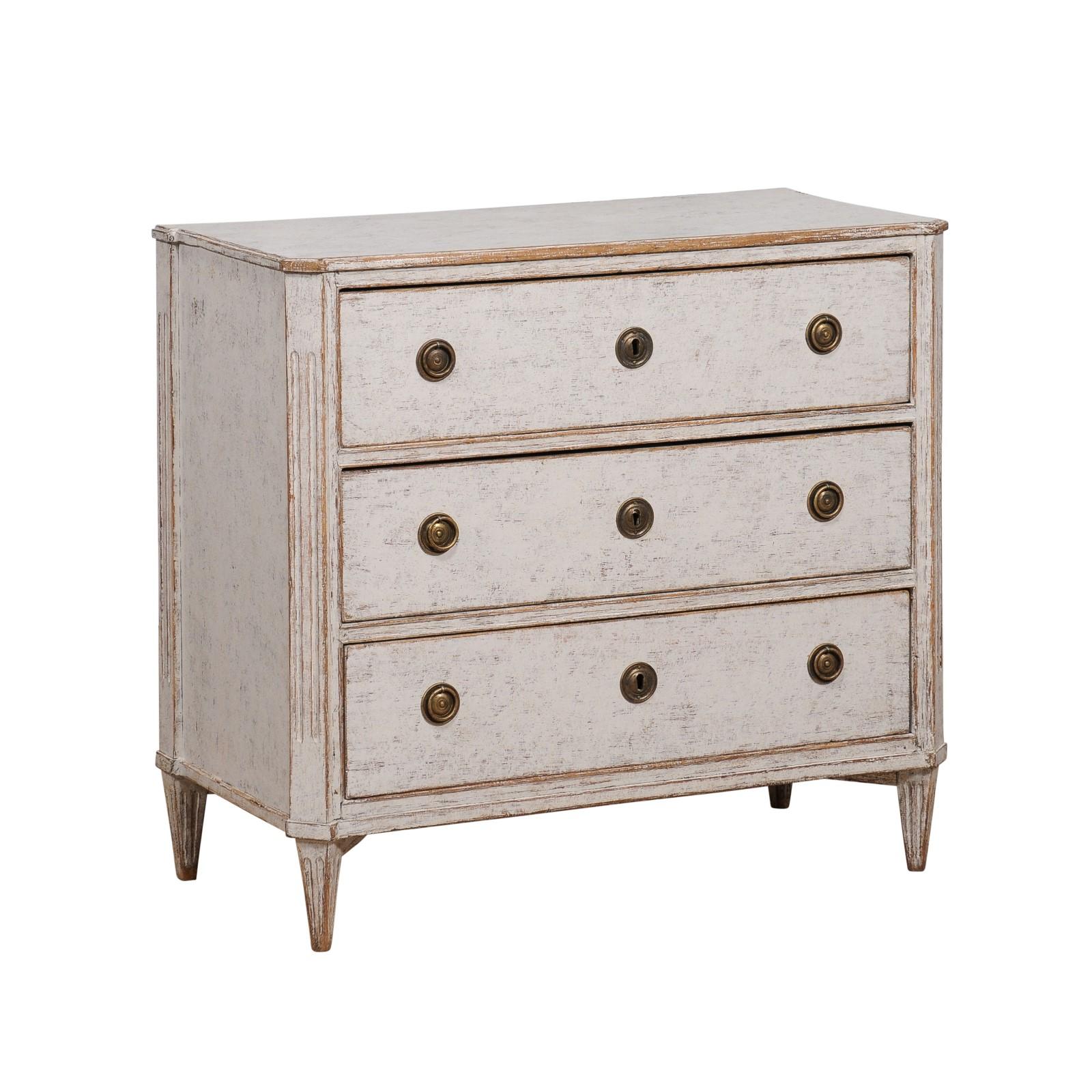 A Swedish Gustavian period light dove grey painted chest from circa 1800 with three dovetail drawers, canted side posts and fluted tapering feet. Evoking the serene elegance of the Swedish Gustavian period, this dove grey painted chest, circa 1800,