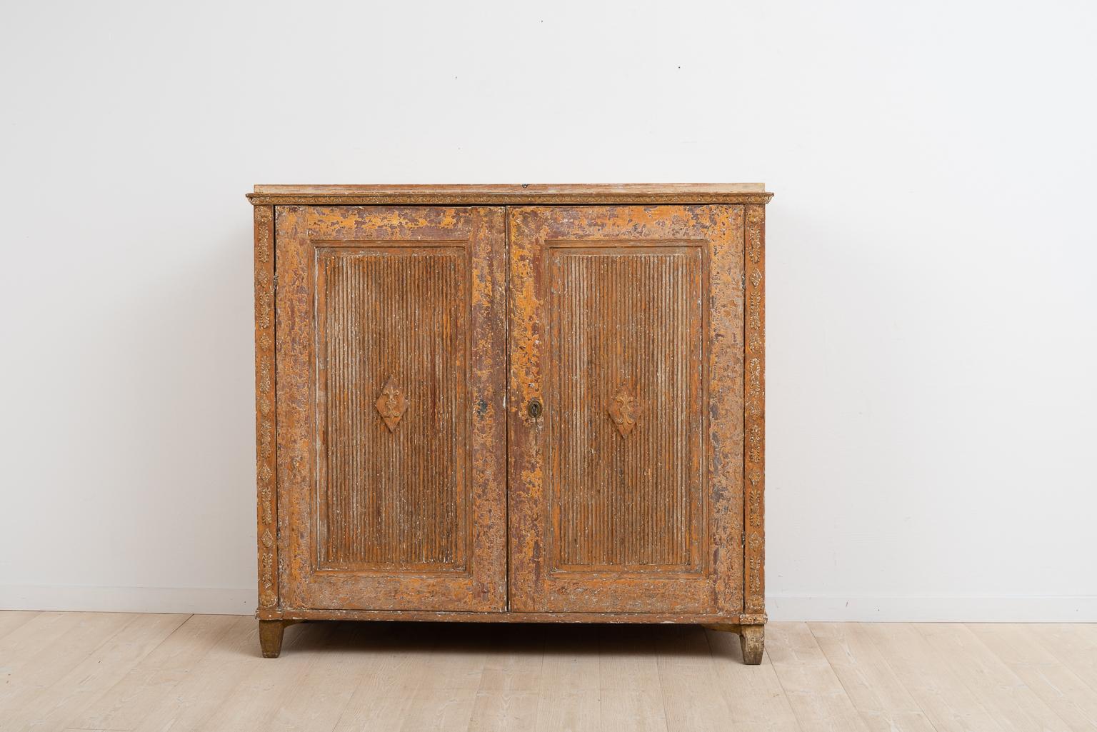 Gustavian sideboard from northern Sweden. Rustic patina. The sideboard has an unusual construction with drawers on the inside. Gustavian decor in the form of pastellage on the doors and sides. There is some smaller damages to the decor on the top’s