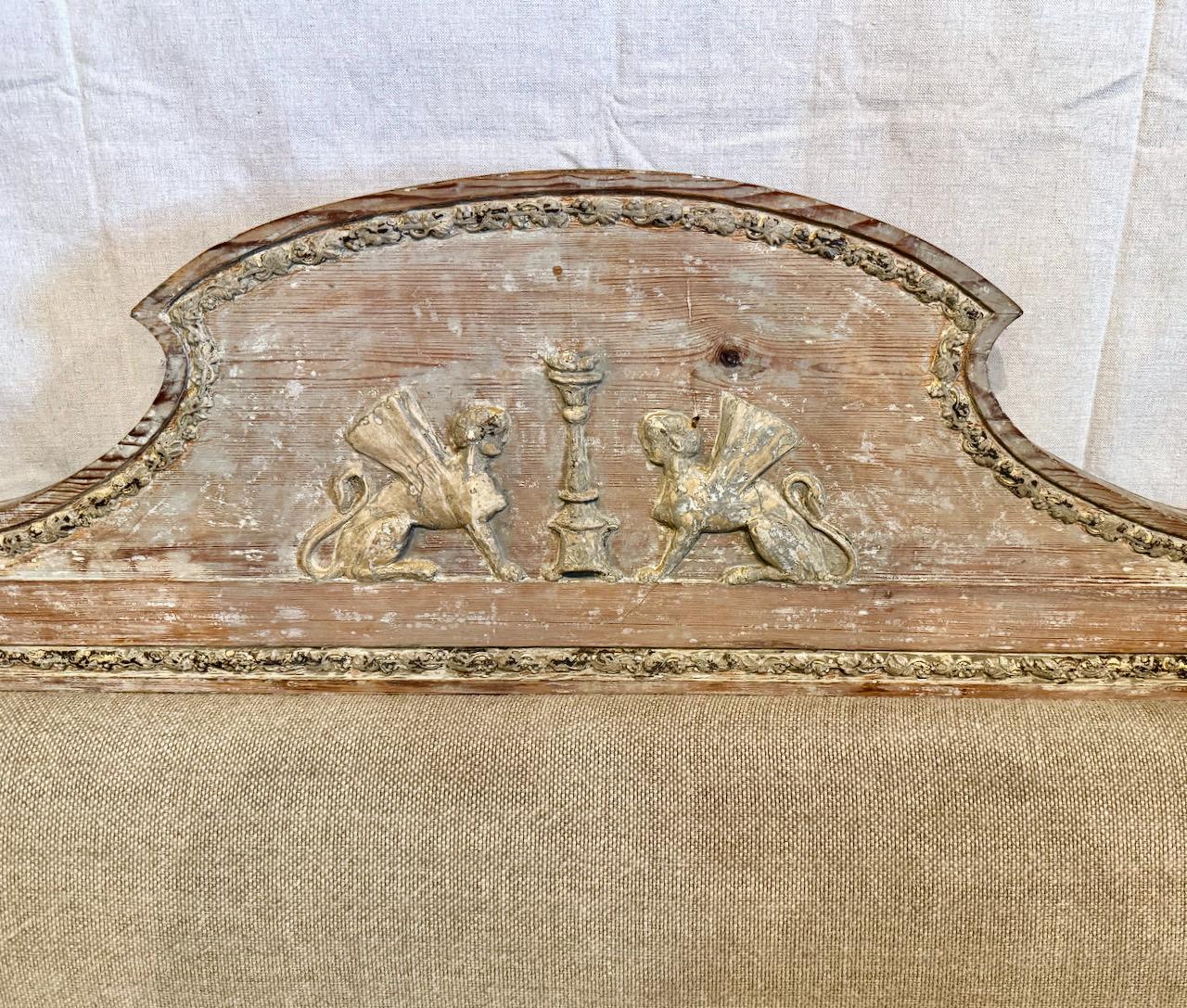 This is an exceptional Early 19th Century Gustavian Sofa, c. 1800-1810. The sofa is in very good condition and it retains its original scraped surface. The raised center back panel features a pair of opposing Sphinxes; the arms are out swept. Carved