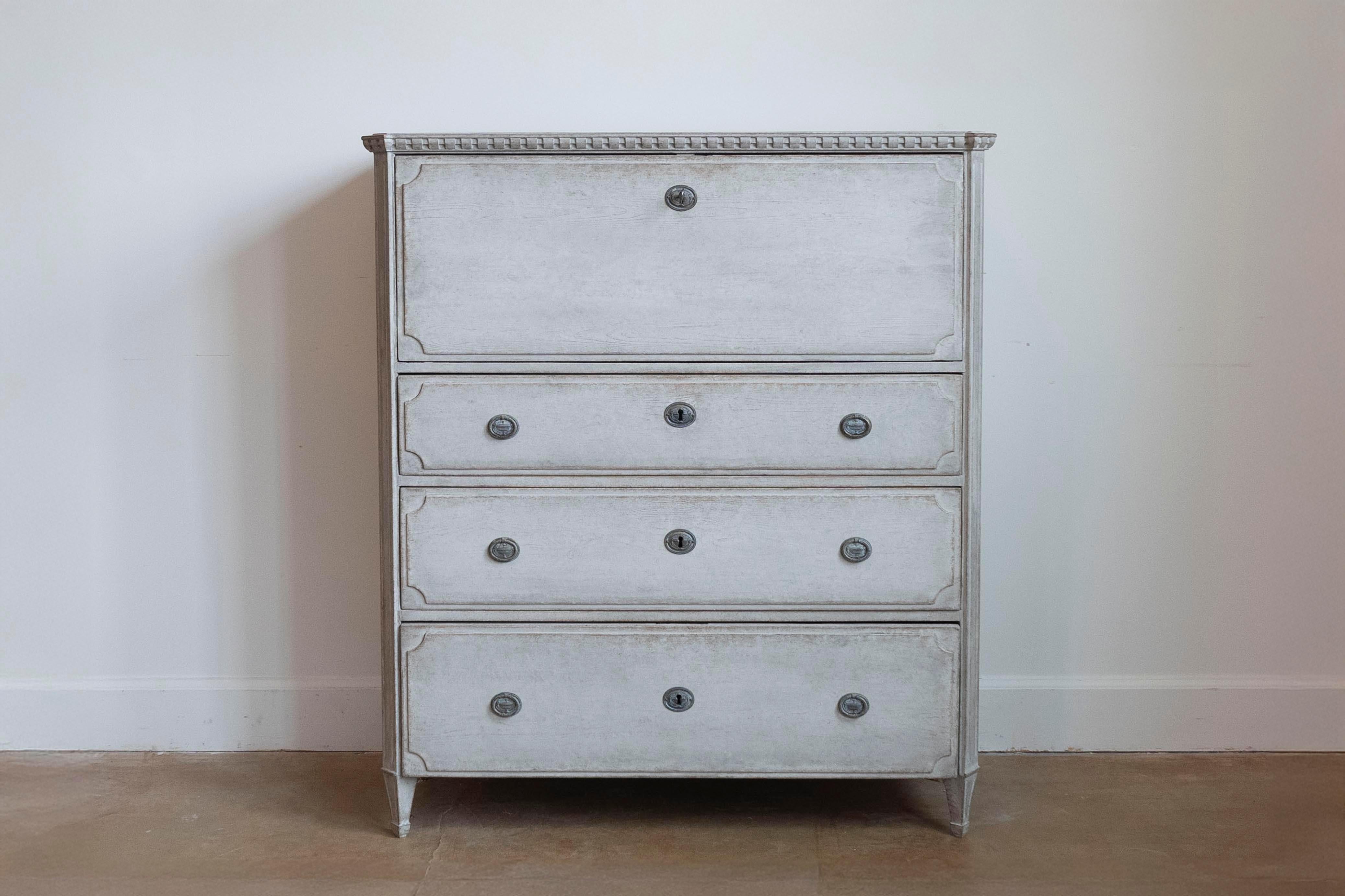 A Swedish Gustavian style drop front secretary from circa 1840 with gray painted finish, writing area and three graduated drawers. This Swedish Gustavian style drop-front secretary, crafted around 1840, is a masterpiece of classical elegance. Its