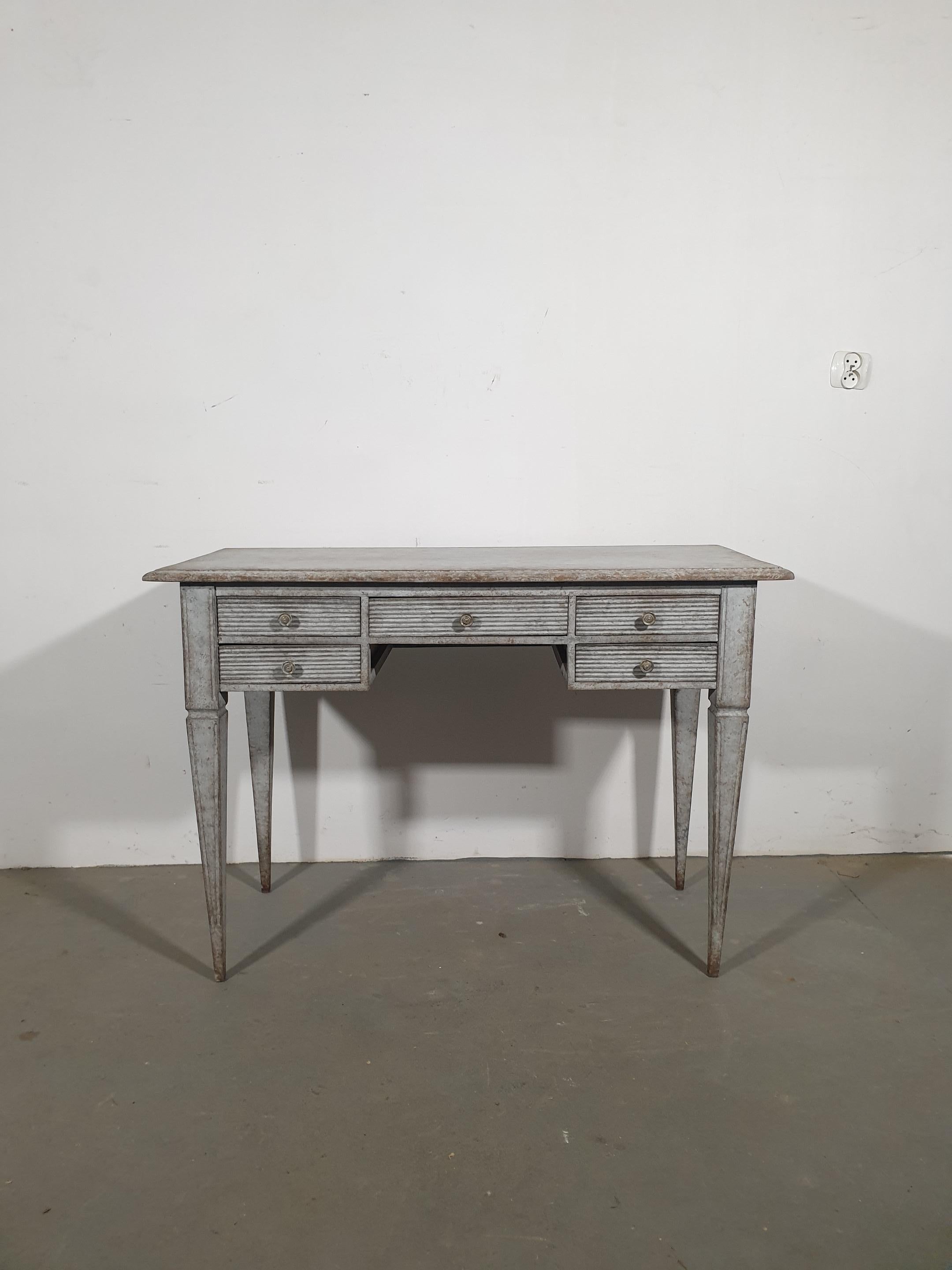 A Swedish Gustavian style gray blue painted desk from circa 1870 with five fluted drawers and tapered legs. Step back in time with this exquisite Swedish Gustavian style desk, dating back to circa 1870. Finished in a cool gray blue hue with quite a