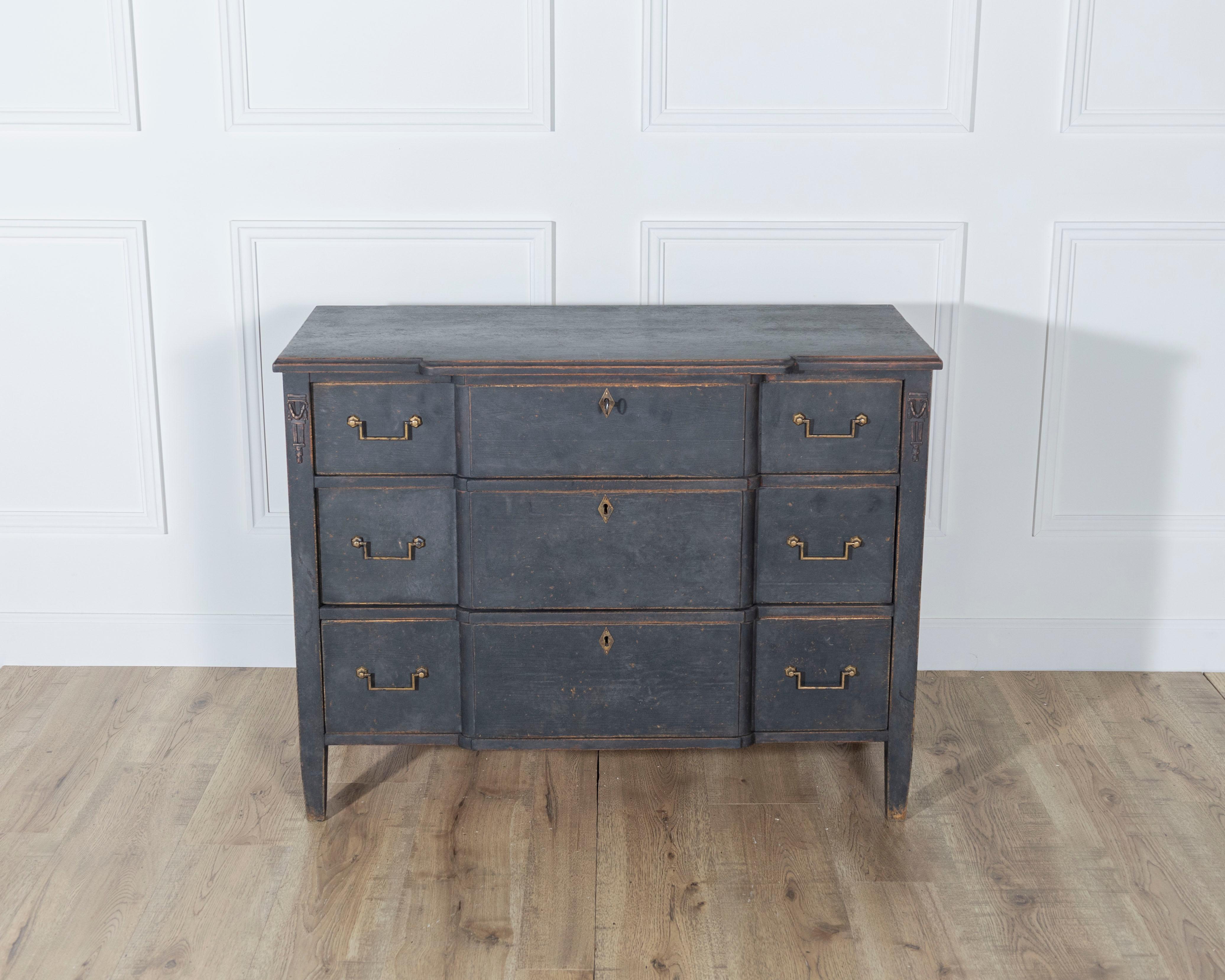 An elegant Gustavian-style chest of drawers, painted in matte black with a gently worn patina that enhances its architectural details. Crafted from a mix of oak, oak veneer, and pine, this early 20th-century piece features a symmetrical arrangement