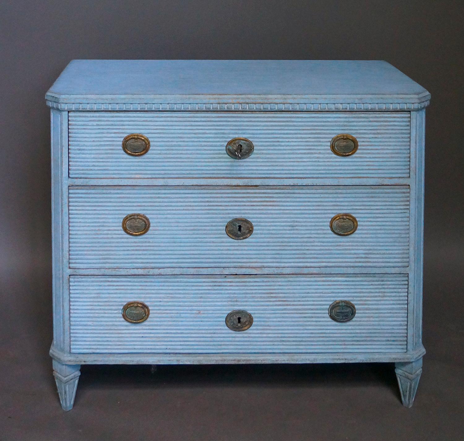 Chest of drawers in the Gustavian style, Sweden, circa 1880, with three reeded drawers. Dentil molding under the shaped top, reeded corner posts and tapering square feet. Period brass pulls and escutcheons.