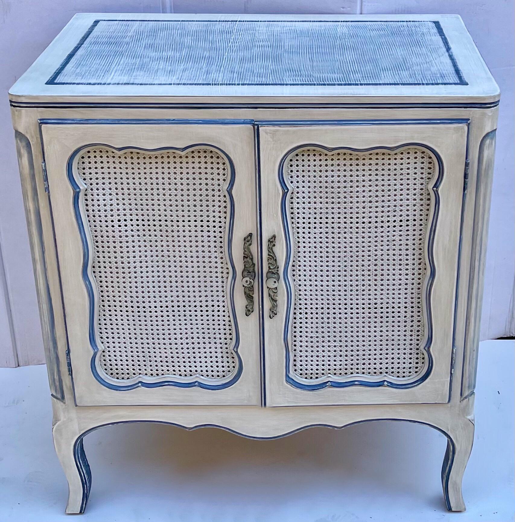 These are a personal favorite! The finish turned out to be wonderful. This is an offering for a pair of mid-century Gustavian style cabinets with caned fronts and three interior drawers. The hand applied finish is a distressed blue and ecru. Note