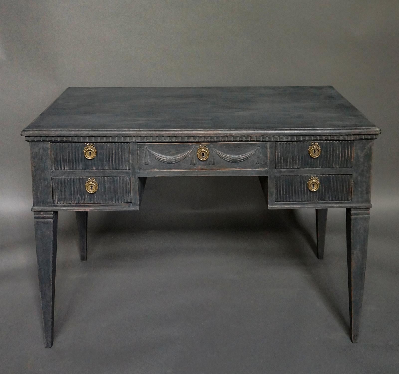 Swedish desk in the Gustavian style, circa 1890. The centre drawer has two beautifully carves swags, and the four side drawers are reeded. Dentil molding under the top and tapering square legs.