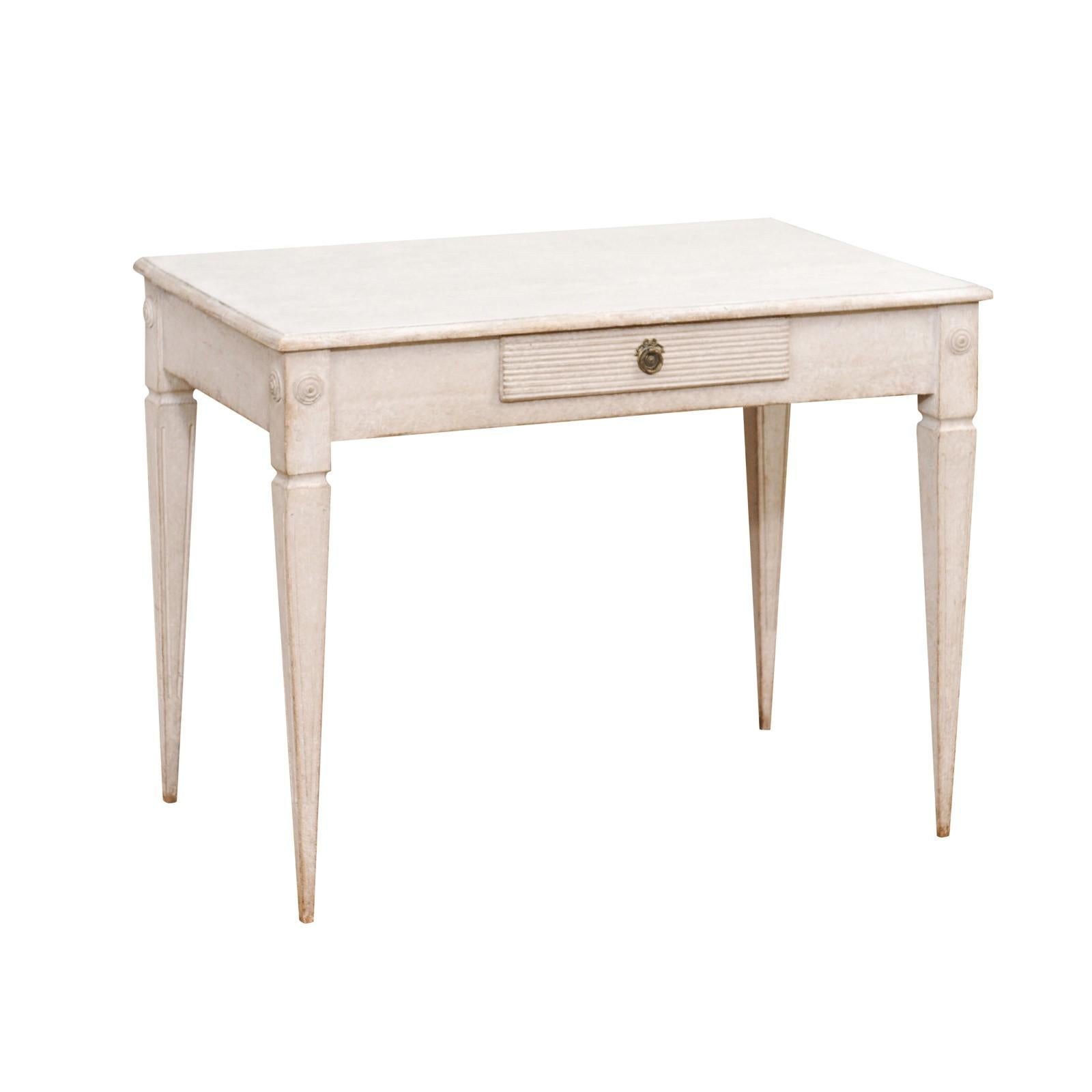 A Swedish Gustavian style writing table from circa 1900 with light gray painted finish, single drawer and tapered legs. This Swedish Gustavian style writing table, dating back to around 1900, exudes an air of timeless elegance with its light gray