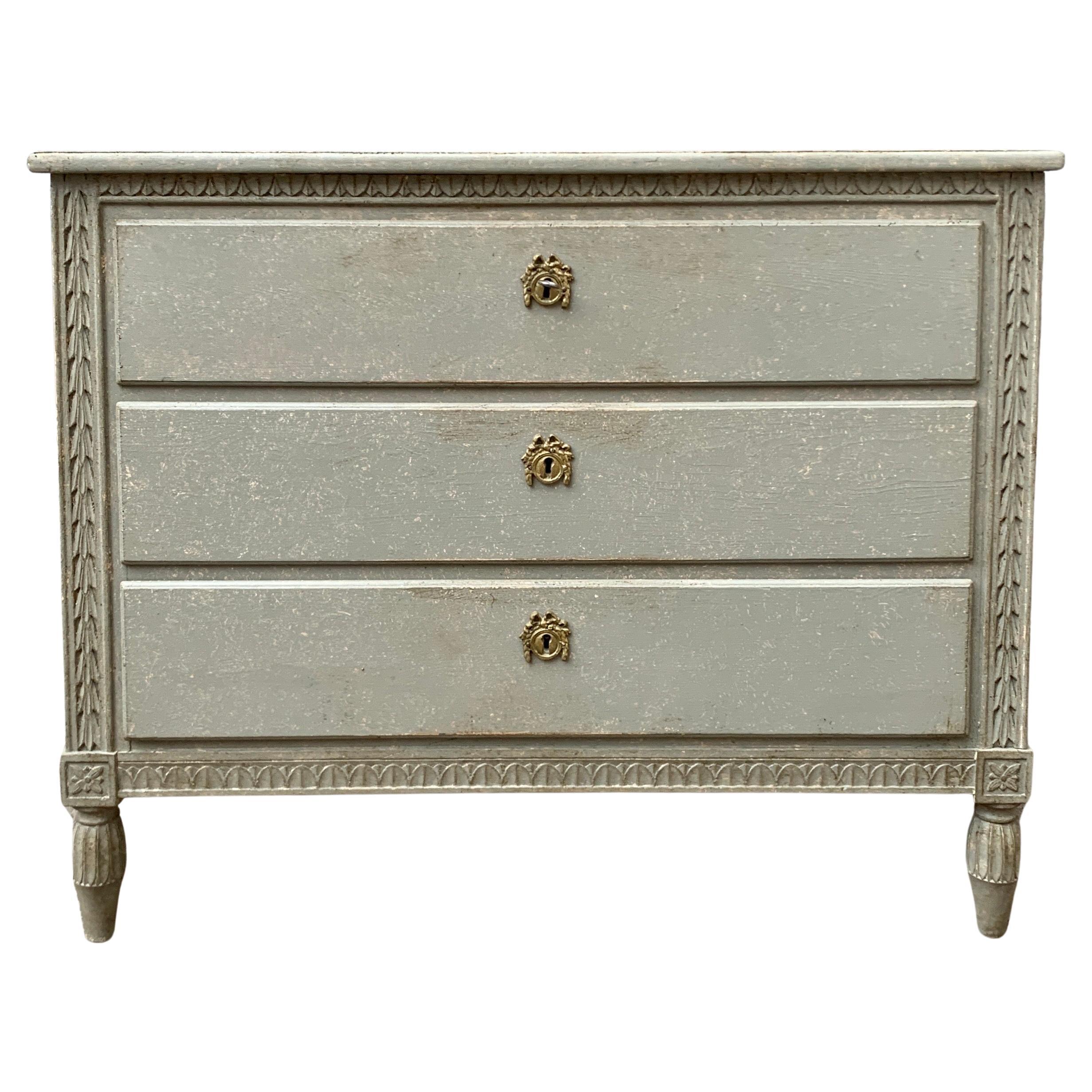 An early 20th century grey painted Scandinavian chest of drawers from Sweden.
This 3 drawer dresser has a nicely carved leaf pattern around the front and on the apron, plus a working original key and locks. It has an extra drawer inside the top
