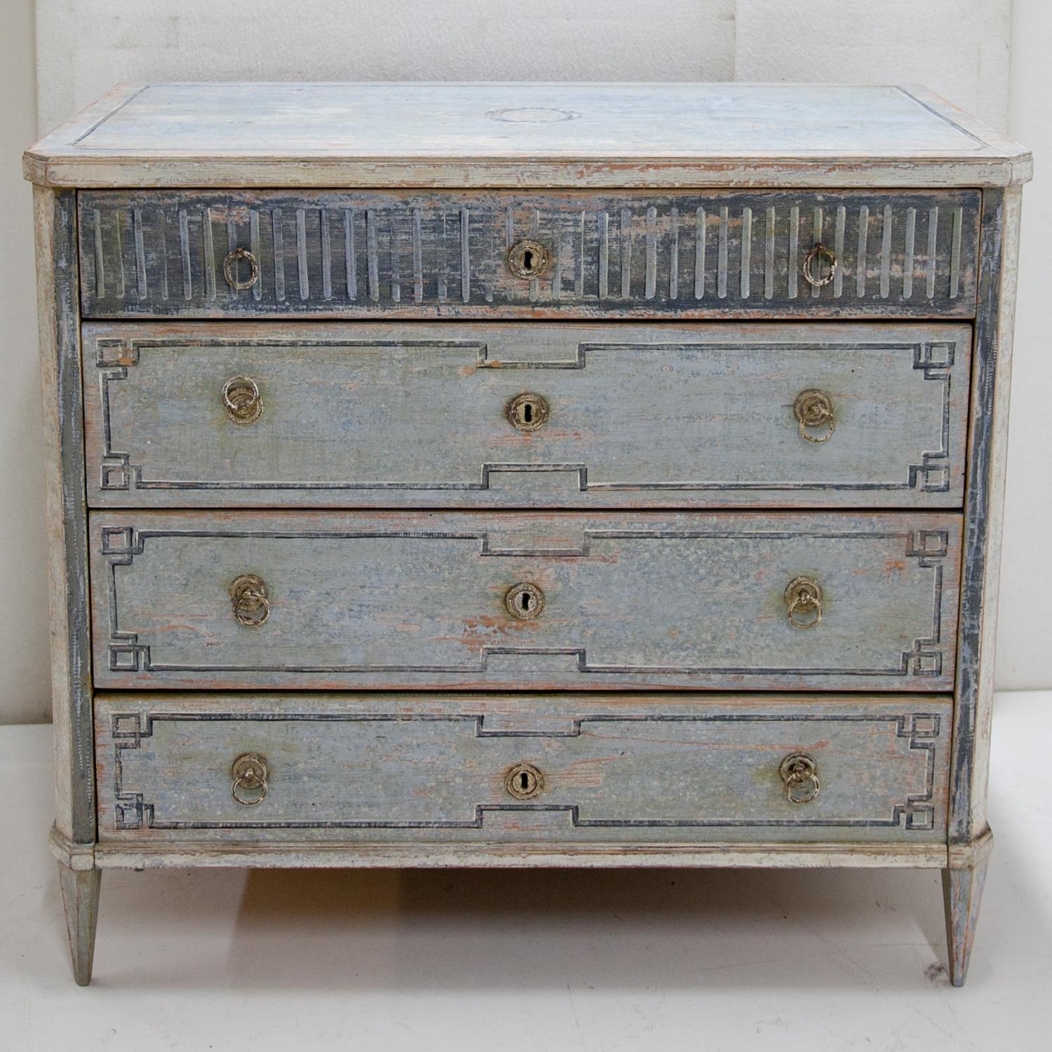 Four-drawered painted chests of drawers with slanted corners, standing on tapered feet. The new blue Gustavian-style paint was done after historical designs and has a distressed patina. Monogrammed P. M. and dated 1878 on the backside.