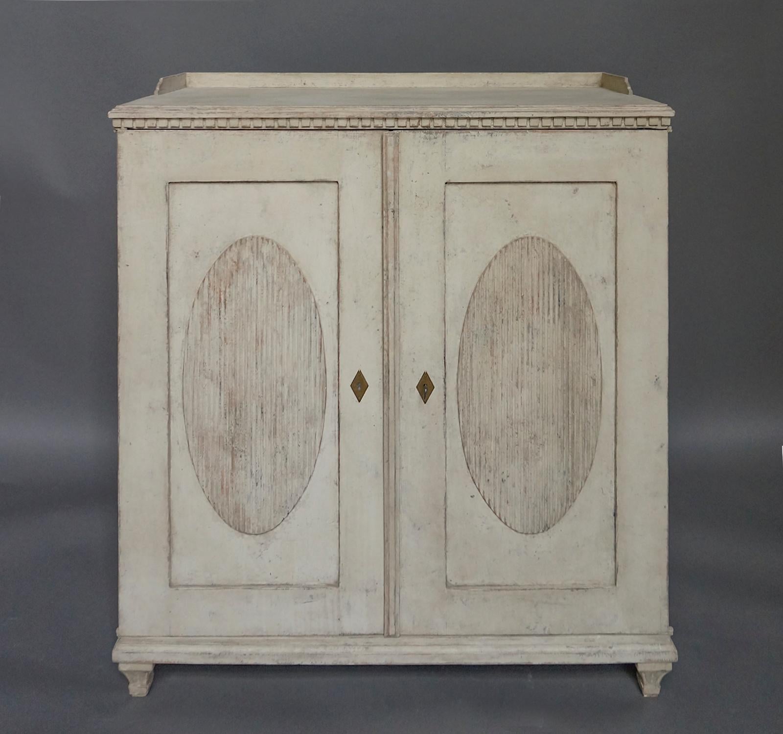 Swedish sideboard in the Gustavian Style, circa 1840. Dentil molding under the gallery top, and two doors with raised and reeded oval panels. The interior has a pair of drawers and two fixed shelves. Tapering square feet.