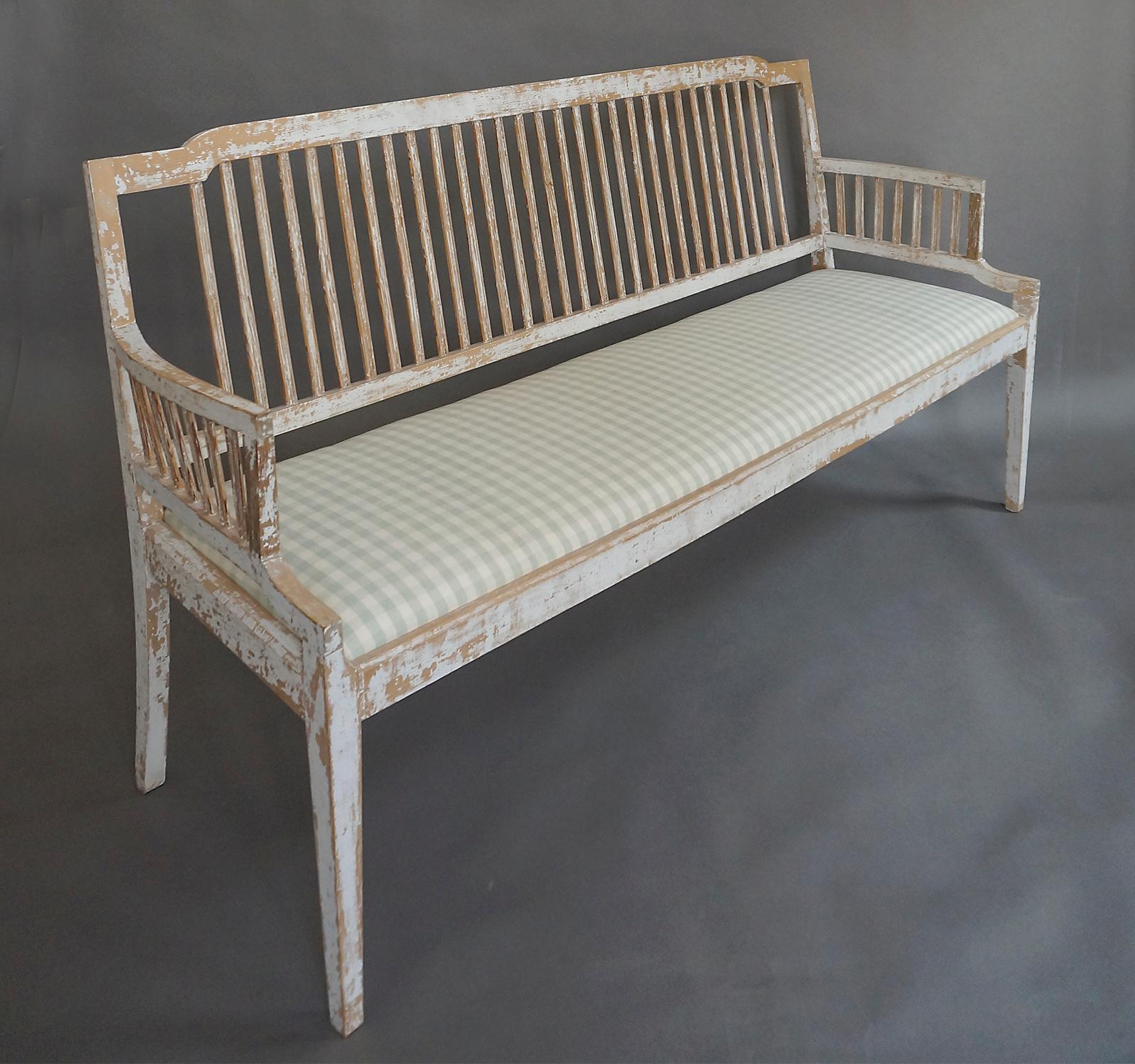 Swedish stick-back settee in the Gustavian style, circa 1860, scraped to the original paint. The slip seat has been newly upholstered in a green homespun linen check.
