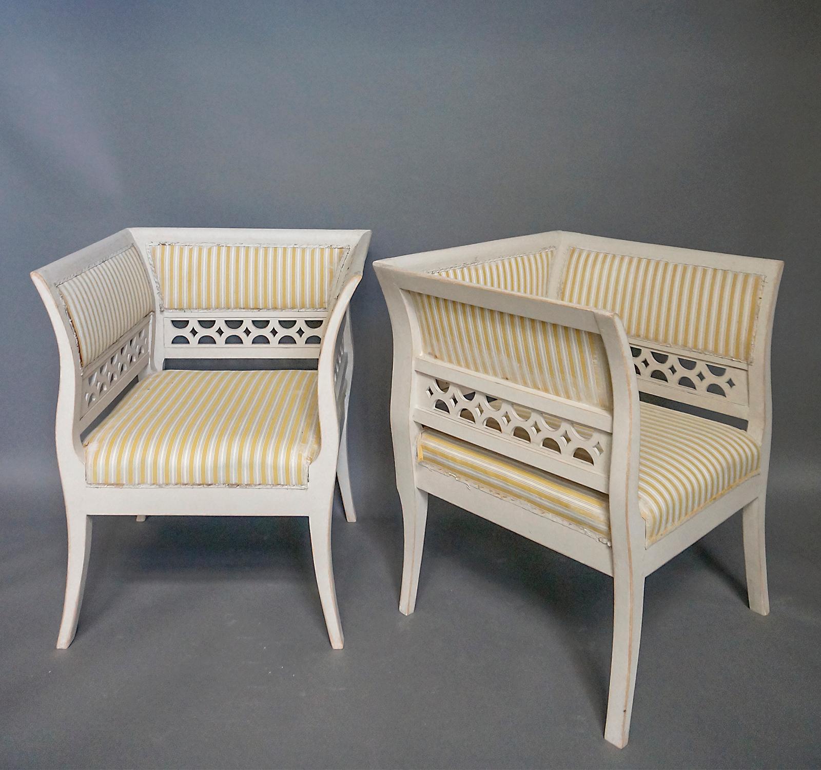 Pair of large armchairs in the Gustavian style, Sweden circa 1910. The high arms and backs are upholstered above pierced panels, and the flaring arms continue into saber legs in an elegant curve. The deep upholstered seats provide a comfortable nook