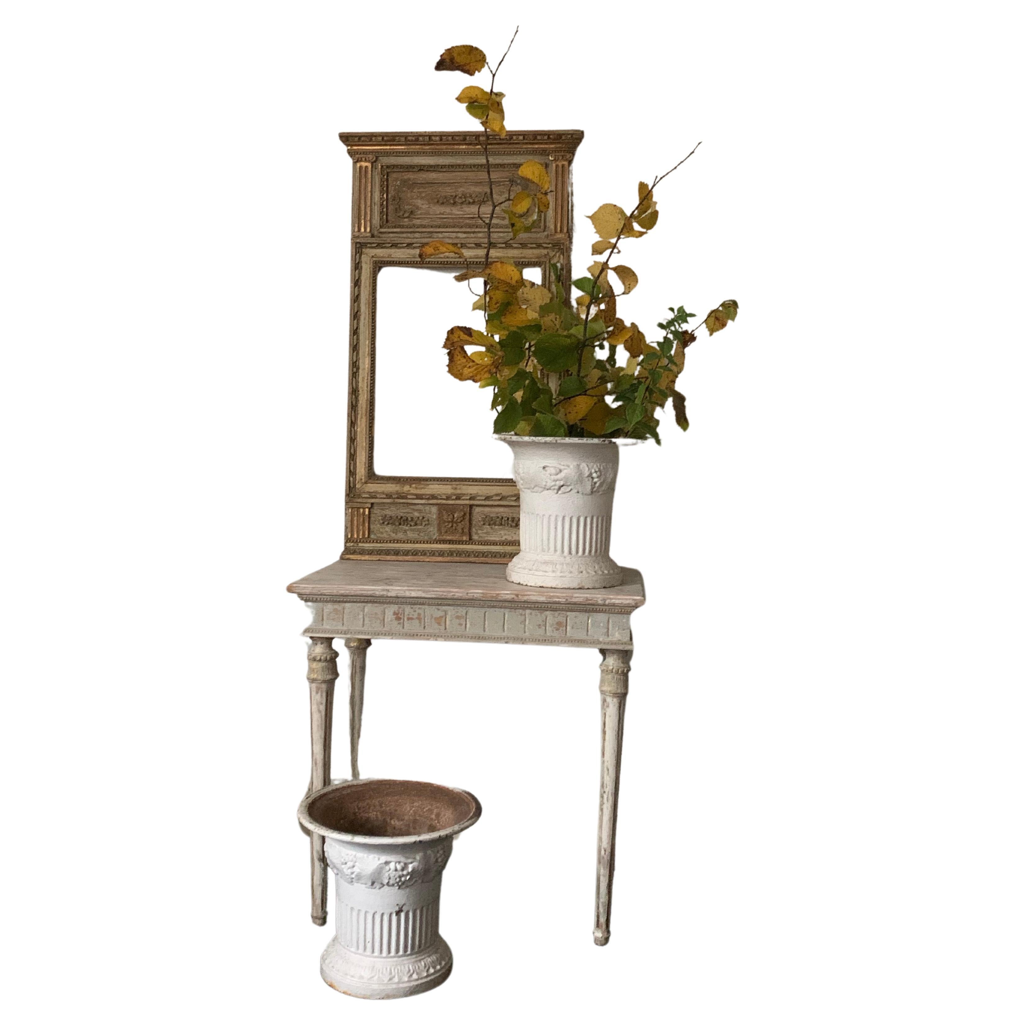 A gustavian table made in Sweden about 1800. The secondary color has been removed by hand and the rest is original color.    
                              
The iron urns are a pair made in France in the second half of 19th century. The urns size