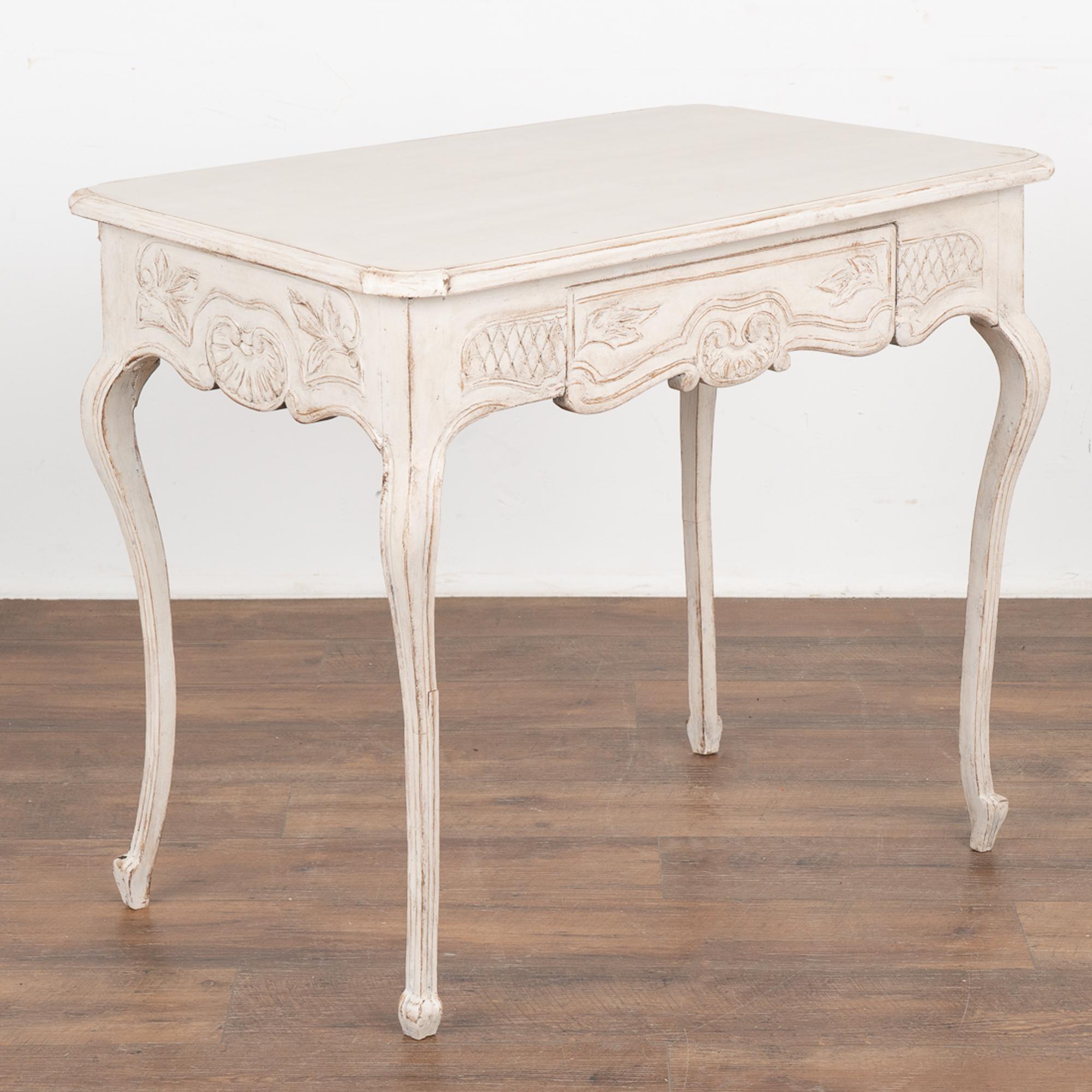 The delicate curved cabriolet legs and decorative carved skirt add a romantic touch to this charming Gustavian side table with single drawer.
The newer, professionally applied layered white painted finish has been lightly distressed to fit the age