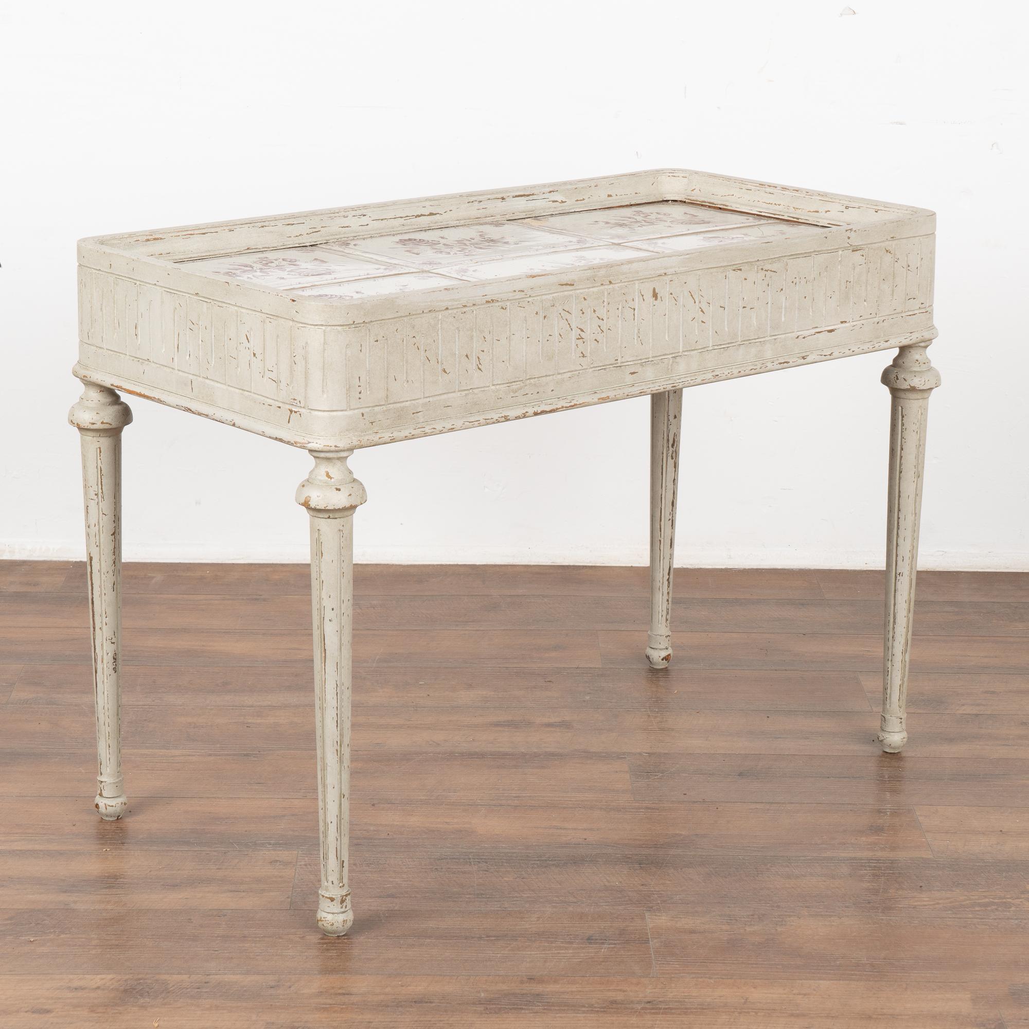Swedish Gustavian tile top side table with tapered fluted legs and raised lip around tile top. Fluted carved details surround the 6.5
