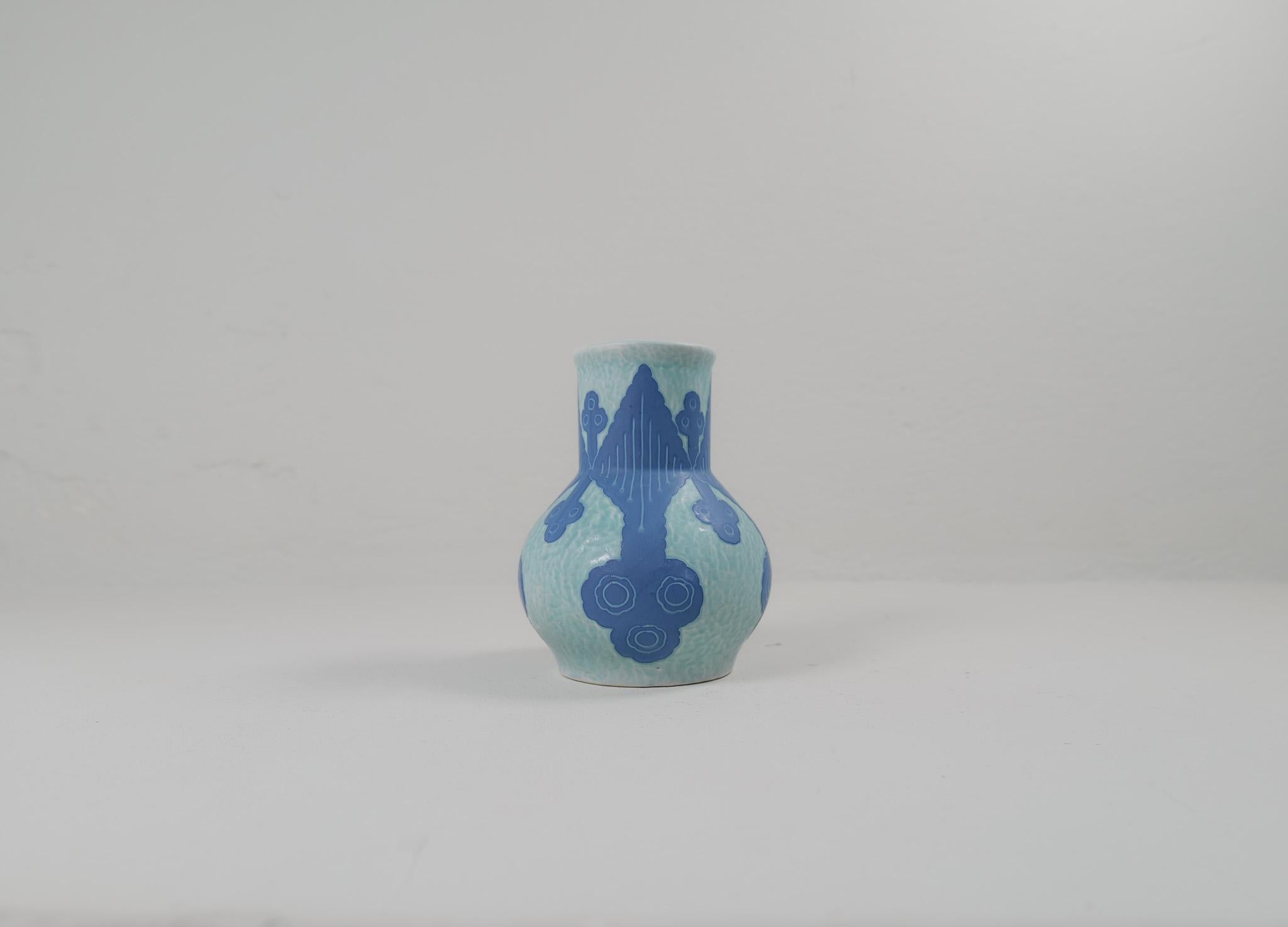 Vase en sgraffite décoré d'un motif floral, par Josef Ekberg pour Gustavsberg.
Le sgraffito est une façon de combiner deux couches pour créer un motif. La deuxième couche est enlevée et il reste un fond bleu clair avec un beau motif sur le