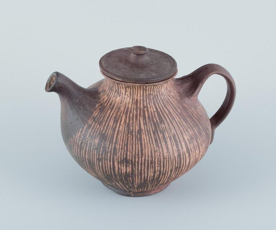 Gutte Eriksen (1918-2008), own studio, Denmark.
Unique ceramic teapot. Raku-fired. 
Glaze in brown and yellow tones.
Approximately 1970.
Signed.
In perfect condition.
Dimensions: Width 22.0 cm x Height 18.0 cm.

Gutte Eriksen was a Danish ceramic