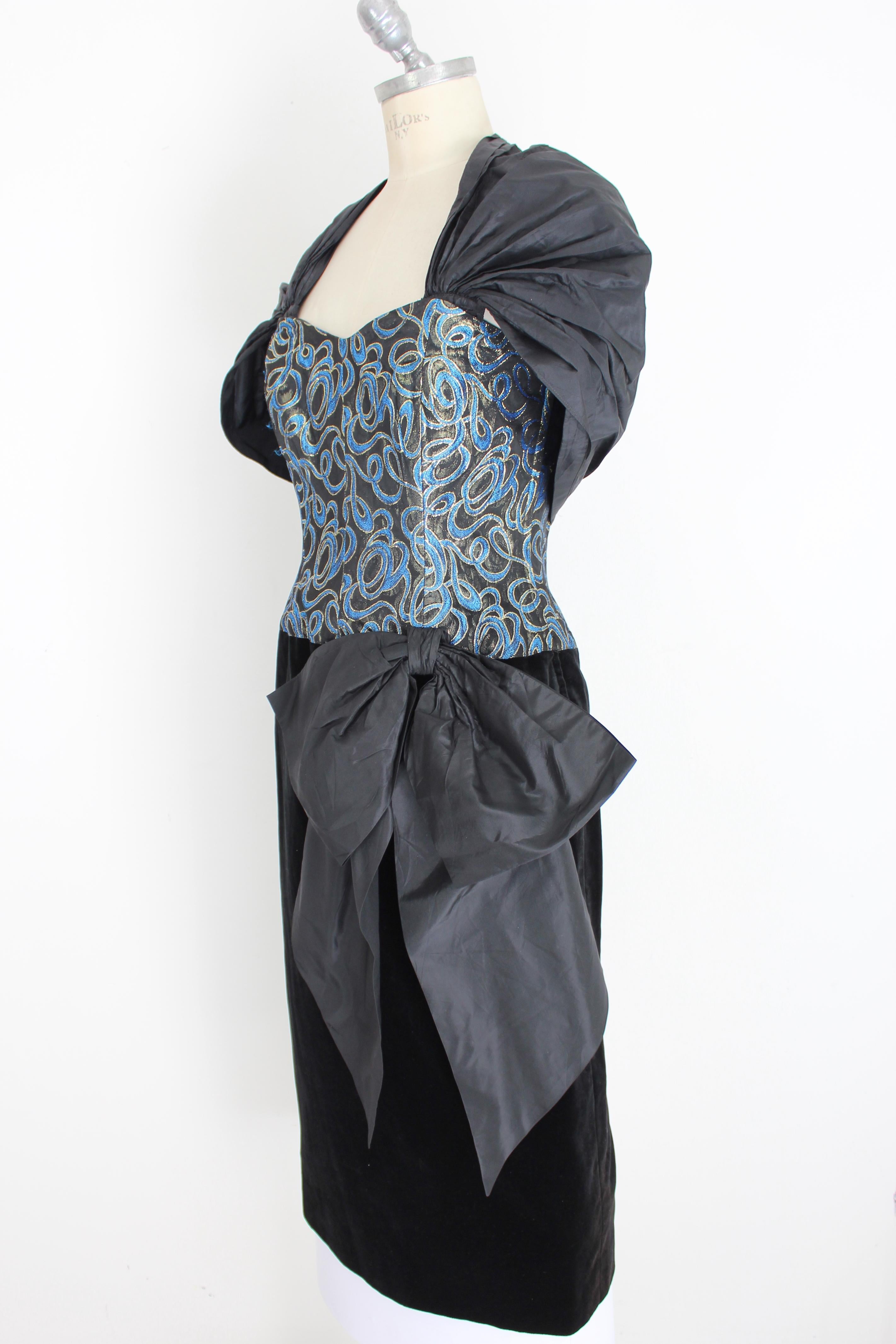 Guy Laroche vintage 70s woman dress. Evening dress, blue and gold damask bodice, internal boning. Black velvet skirt, on the side a large bow. Removable shrug with clip buttons. Fabric 63% acetate, 29% viscose 8% polyester. Lined interior with 73%
