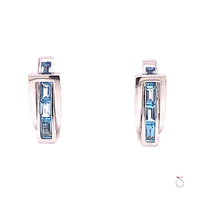 French Designer Guy Laroche Aquamarine huggie earrings in 18k white gold. These earrings have a unique pass through design. The beautifully designed earrings features four (4) rectangular cut blue Aquamarine gemstones set in a channel that passes