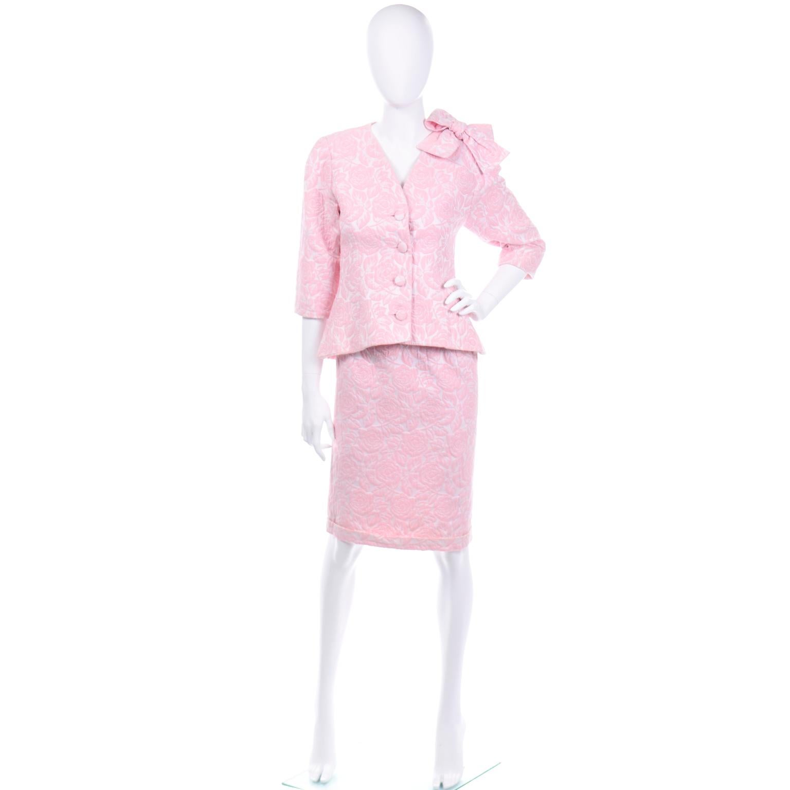 This is a very pretty pink floral brocade skirt suit from Guy Laroche Boutique. This 2 piece outfit would make a great day dress alternative to wear as a wedding guest or to a special lunch or event. The jacket has a high v collarless neckline with