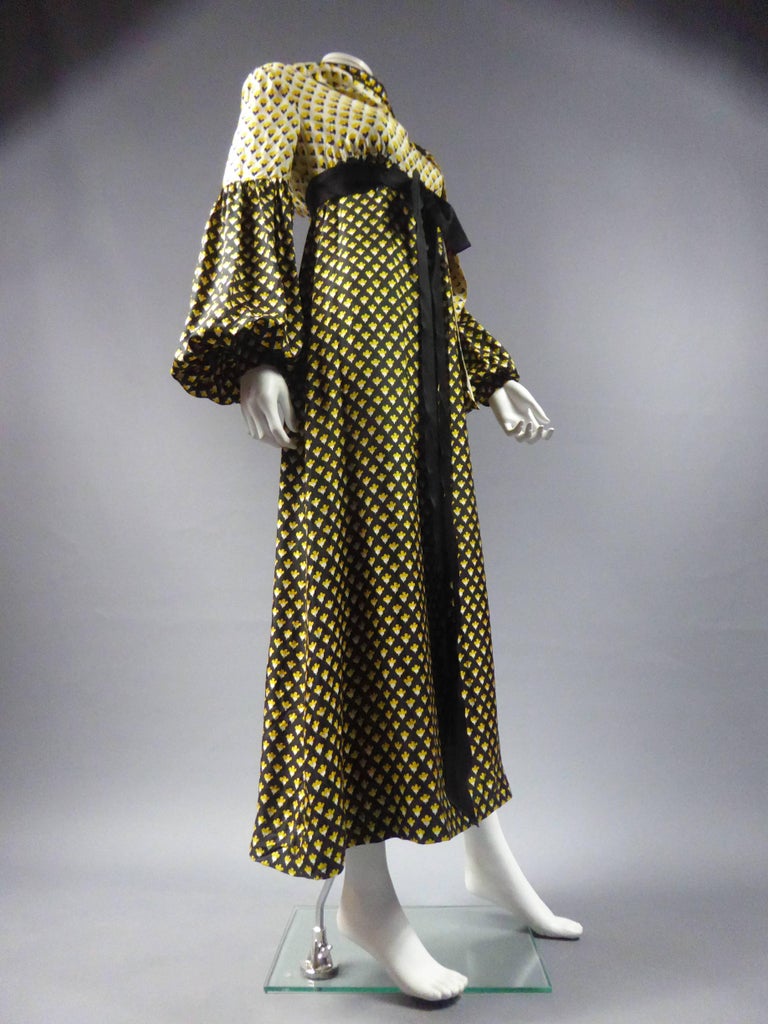 Circa 1970
France

Long printed silk dress by Guy Laroche. Printed with reverse effect of negative / positive. Empire waist dress highlighted by a belt under the chest in a black satin ribbon bow. Long dress with flared skirt, black fabric strewn